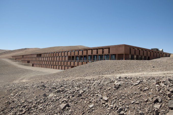 fasc1nate's tweet photo. In the heart of Chile’s Atacama Desert lies the stunning ESO Hotel. Prominently featured in the 2008 James Bond film Quantum of Solace, this hotel is not open to the public but serves as accommodation for researchers at the European Southern Observatory.

The ESO Hotel is designed to blend seamlessly into the desert landscape, minimizing its visual impact. It is nestled within a natural depression, with only its central garden dome visible on the horizon.

Constructed primarily from concrete, as brick and steel were economically impractical and unsuitable for the desert environment, the hotel offers 108 rooms, 18 offices, a sauna, gardens, swimming pools, and a library. It has earned the nickname "Oasis for Astronomers."

Situated at an altitude of 2,400 meters, and receiving less than 1 cm of rainfall annually, water had to be transported by tankers to mix the concrete during its construction. Even now, the complex depends on regular water deliveries to remain operational.

More fascinating resorts around the world: https://t.co/oVya8wYCYl
