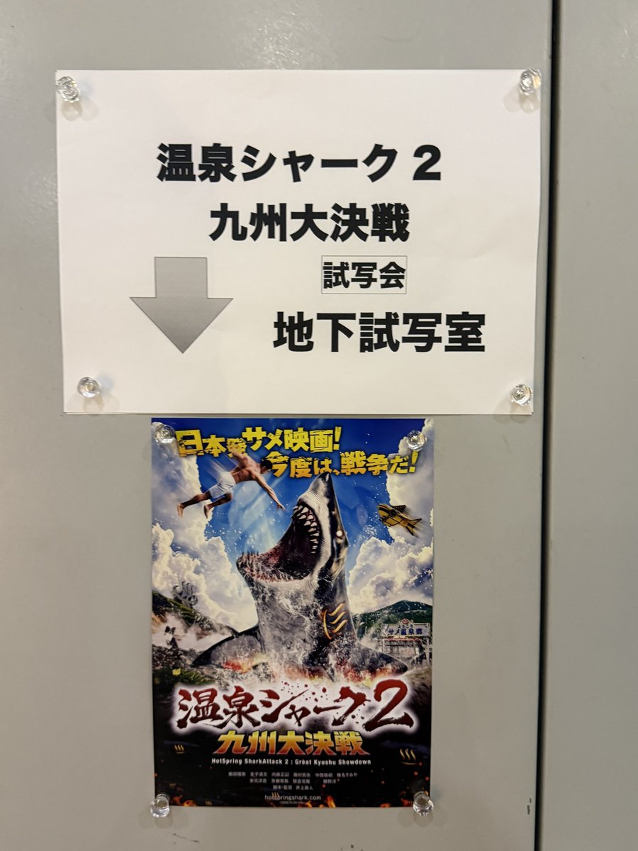 Munenori20's tweet photo. 試写で『#温泉シャーク2 九州大決戦』拝見したので簡潔に感想を。

サメ映画史を追う者として、まずは歴史的な背景について触れさせてください。サメ映画50年の歴史の中で、様々なサメ映画が生まれ、先人たちは道なき道を切り拓いてきました。「希望とは、もともとあるものともいえぬし、ないものともいえない。それは地上の道のようなものである。もともと地上には道はない。歩く人が多くなれば、それが道になるのだ」、そう魯迅は『故郷』で語りましたが、これはサメ映画の歴史そのものと言えま���。
『ジョーズ』の軛からサメを解放したのは、『シャークネード』であるのは周知の通り��す。恐怖の象徴だったサメは、竜巻に乗って空を飛び、人々に笑いをもたらすエンターテイナーに姿を変えました。その頃からサメ映画におけるサメはシリアスなキラーと不条理なコメディアンという、『ダブルヘッド・ジョーズ』さながらに２つの顔を持つようになります。
『シャークネード』が切り拓いた道には、サメであることをやめた後進が次々に現れました。しかし、これは一つの陥穽でもあったのです。ハイコンセプトな方向に舵を切ったサメ映画たちの前には、常に『シャークネード』が立ちはだかりました。極限まで予算を削りゲリラ戦に身を投じたZ級サメ映画たちは隆盛しましたが、一般的な視聴に耐えうる予算をかけながら、『シャークネード』ほどに正気を失えたサメ映画は、結局その続編しかありませんでした。ニーチェが「怪物と闘う者は、その過程で自らが怪物と化さぬよう���せよ」と述べたように、解放者はいつのまにか大きな壁になっていたのです。
『シャークネード』の本質は、 “ありえなさの追究” にあります。ネード世界ではたまたま海を泳いでいた大量のサメが巨大ハリケーンに巻き上げられ人々の上に降り注ぎます。やがてサメを伴った台風は勢力を増し、宇宙に進出したり世界を滅ぼしたり時空を超えるようになっていきます。目の前で起こる信じられない事態が、視聴者を置き去りにして全力で明後日の方向に駆け抜けていくことの快感。それこそが数多くのシャークネーダーを産んだ原動力でした。そしてその快感の高みこそが、後続にとっての壁になっていたのです。
こんな分厚い壁に極東から立ち向かったのが、米国生まれのサメ映画という概念を見事にローカライズした『温泉シャーク』です。日本��深く根付いた温泉文化をベースに、��撮でサメ映画を撮るという試みは、サメ映画界隈のみならず多くの賛同者を生み出しました。ありえない嘘を真剣につき、時たま嘘をつくことを諦める姿勢には、確かにサメ映画スピリットが宿っています。
前作の時点で『温泉シャーク』はサメ映画界の絶対王者の玉座に手を伸ばすことが出来ていたと思います。しかしこの『温泉シャーク2』は、その王位を奪い取ってしまいました。本作は九州全土を舞台にし、筋肉、特撮、サメ、キャスト、音楽、あらゆる点でスケールアップしていますが、特筆すべきは正気を疑う脚本です。ひとたび本編が始まれば、観客に思考は許されません。「なんて？」「なんで？」「そうなの！？」「そっかぁ！」という知能剥奪サイクルが数十セットも繰り返されることで、観客は温泉シャークの世界にのめり込むように調教されていきます。そしていつの間にか、訳の分からない展開を手に汗握りながら見守ることしか出来なくなっていくのです。常識という名の森には上映開始数分で火が放たれ、中盤には焼け野原となり、それでも何かが燃え続け、最後には素晴らしいテーマ曲とともに「いやなんか凄いものを観た気がするけどこれは何？」という大きな疑問と感動が残ります。
これからご覧になる方は、ぜひどのシーンでもいいので人に説明してみてください。あり得なさすぎて誰も信じないと思います。そんな信じがたいことが88分間、連続で起こり続けます。もちろん前作を観てからの鑑賞をお勧めしますが、そういう感じの作品なのでスタート地点は結局同じです。「まずは予習してから」などと宣う非温泉シャーク者をバシバシ劇場に連れ込み、思うがままに蹂躙される九州に頭を抱えさせてください。
サメ映画の魅力は、「思いつい���ことを映画にしてみる」というクリエイティビティの爆発にありますが、狂人でなければ思いつかないことを映画にされては、もはや我々に打つ手はありません。その意味で、『温泉シャーク2』はサメ映画の王を名乗っても決して不遜ではないでしょう。
『BAD CGI SHARKS 電脳鮫』という作品では、「サメ映画の歴史は『ジョーズ2』から始まった」と語られていますが、『温泉シャーク2』は新たなサメ映画の歴史を開闢したのです。ですが果たして、温泉シャーク製作陣はいまや自分たちが新たな怪物と化したことに気づいているのでしょうか。サメ映画の道は常に獣道です。付き合わされる観客も、たまったもんじゃないですよね。