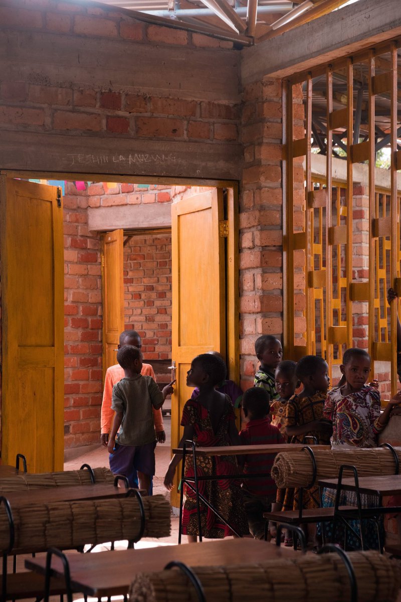 shavnyuyngah's tweet photo. When people build or donate infrastructure in Africa, they scarcely read the environment, and even most African architects scarcely do it either. The result is boxy buildings with tiny openings, painted white or some bright color to look finished. Rain and harmattan dust wear that paint down fast, and repainting or repairing it is upkeep most local communities cannot sustain. So the buildings age badly, not because the climate is harsh, but because the design never accounted for who would maintain it.

The reverse is true for this Tanzanian project.

Wayair School, Ulyankulu, a former refugee settlement in western Tanzania. Jeju Studio, a Polish practice, designed it for the Wayair Foundation. The building is made of locally crafted brick, fired from two different clays, dark red made onsite, lighter red made in a nearby valley, arranged into a gradient rather than painted over. Nothing here needs paint to survive weather, the material carries its own finish and ages into the landscape instead of against it.

The classrooms sit around a courtyard wrapped around existing mango trees, modeled on the local Saturday market where the whole community already gathers under big trees. Roofs are pitched with a ventilation gap at the peak, thick concrete floors hold the classrooms cool through the day, no mechanical cooling anywhere. A 70,000 litre rainwater harvesting system, filled in one short rainy season, carries the school through nine months of dry season.

This is what happens when a design team reads the site, the climate, and the community before drawing a single wall.

Architect: Jeju Studio
Location: Ulyankulu, Tanzania
Client: Wayair Foundation
Photography: Iwo Borkowicz