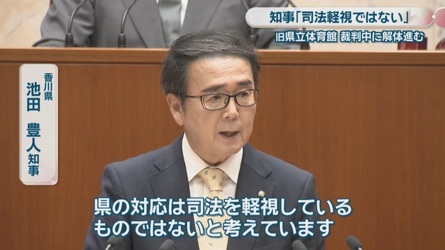 yutani_LAN's tweet photo. 「あなたが今壊しているものは、裁判の証拠なのですが」

旧香川県立体育館。1964年、丹下健三の設計で完成した。船が浮かぶような屋根の形から「船の体育館」と呼ばれ、世界の建築史に名を残す建築である。
MoMAもハーバードもDOCOMOMOも保存を求めた。民間からの再生提案もあった。県はすべて退けた。理由は耐震性である。その耐震性の評価と解体費用の支出差し止めを求める訴訟を起こした。裁判は今も続いている。さらには周辺住民による訴訟も起きている。

そんな中で2026年4月10日、県は解体工事に着工。

「法律の専門家の意見も聞きながら適切な対応を検討している」池田豊人知事が、香川県議会で述べた言葉である。何を検討しているのか。
裁判所が証拠保全の判断を下すころ、保全すべき対象物が消えているのではないか、と問われて、である。

つまりこういう質問だ。「あなたが今壊しているものは、裁判の証拠なのですが」
答えは「検討している」。

答えになっていない。
検討という日本語は便利だ。何もしていないことを、何かしているように聞こえさせる。しかも県は何もしていないわけではない。全力で壊している。
着工から3カ月、石庭も石垣も植栽も破壊完了。6月から内装解体。9月には本体に手が入る。
検討しながら、これだけの成果を上げている。行政の生産性向上とはこのことか。

原告側は建物の耐震性を鑑定するため証拠保全を申請した。高松地裁は専門委員5人の助言を受け、必要性を早急に判断するという。認められれば工事は中断する。

中断する。その時、何が残っているのか。

法律の専門家に聞いたそうである。何と聞いたのだろう。「判決前に証拠を消したら違法ですか」だろうか。あるいは「どこまでなら壊してもセーフですか」だろうか。
まさか後者ではあるまい。専門家に聞いたのは適切な対応の検討のためであって、適切な破壊の限界を確認するためではないはずだ。たぶん。

刑事事件でこれをやると、証拠隠滅という名前がつく。行政がやると、適切な対応の検討という名前になる。同じ行為に二つの名前があるのは日本語の豊かさだが、豊かすぎて意味が消えている。

知事は言う。「司法を軽視しているものではない」

軽視ではない。軽視するには相手を認識せねばならない。県は裁判所も住民も文化的価値も認識していない。
壁の向こうで誰かが何か言っている、程度の扱いだ。高さ5メートルのフェンスは、県民の視線だけでなく、司法の視線も遮っている。

裁判所が判断を下すころ、県はこう答えるだろう。「適切に対応いたしました」
事実である。何ひとつ残っていないのだから。