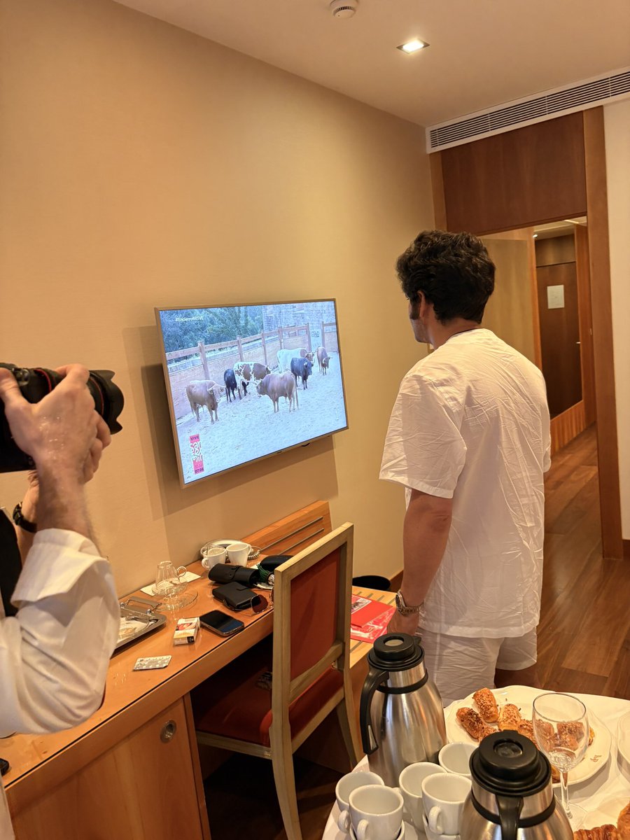 zabaladelaserna's tweet photo. Fervor en el encierro de San Fermín por Morante de la Puebla 

Morante de la Puebla siguió en el cuarto encierro de San Fermín desde un balcón del Gran Hotel La Perla, en la calle Estafeta de Pamplona. 
Antes de que estallase el cohete de salida en los corrales de Santo Domingo, los corredores que pasaban bajo el balcón saludan a Morante, coreando su nombre. Y el maestro saludaba, en pijama, café en mano, a la multitud que esperaba a los toros de Álvaro Núñez que lidiará por la tarde, junto a Borja Jiménez y Pablo Aguado. La expectación es máxima en su vuelta a Pamplona y la reventa está por las nubes. 
Desde los edificios de enfrente también saludaban a José Antonio Morante, que hacía así con la mano, correspondiendo a todos. 
La carrera fue rápida, peligrosa, más a la antigua usanza, y Morante disfrutó del encierro. Que vio repetido en televisión con una sonrisa. El maestro manifestó que preferiría que no hubiera antideslizante y que las cosas fueran como antes en el encierro, con más emoción. Como fue precisamente éste. Parecía que lo hubieran escuchado.  Después del madrugón, subió a descansar  su habitación en un piso superior de La Perla. Esta tarde la Monumental de Pamplona que rindió en 2025 -ayer, 9 de julio hizo justo un año- espera con enormes expectativas. @ElMundoToros 
@elmundoes
