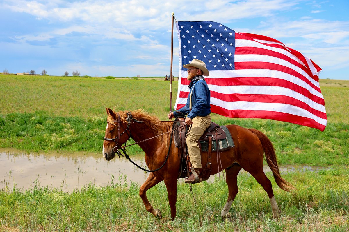 conocophillips's tweet photo. In North Dakota, a Rough Rider reenactor carries the American flag during inaugural events for the @TRPresLibrary, which opened July 4. ConocoPhillips is honored to support the library’s vision through a conservation agreement at Elkhorn Ranch and a $5 million contribution. Explore our Big Picture gallery: https://t.co/IK6oUZGKDy