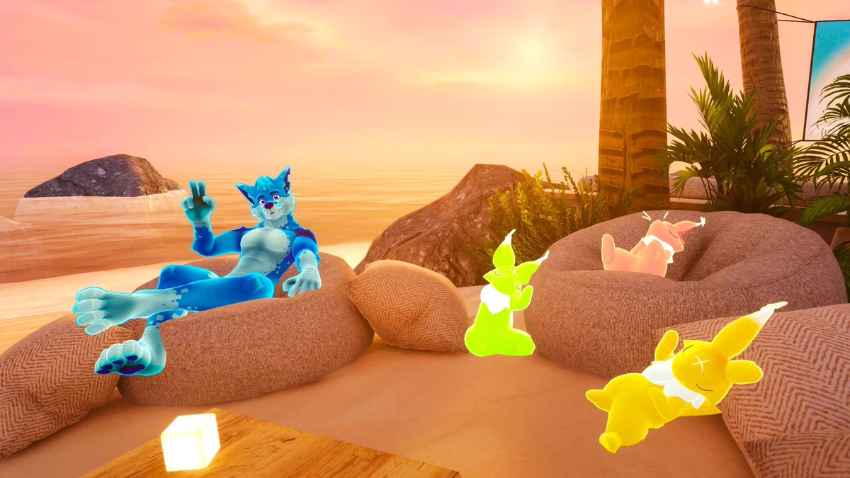 VRChat screenshot. F.Y.N.N., Furality's blue, vulpine mascot, is lounging on a bean bag situated on the sand. Next to him, three bichi's, colorful fox-like creatures, are lounging next to him on another bean bag. The setting is a tropical beach during sunset.