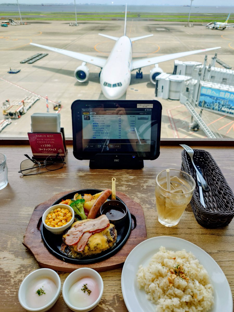 Hiro521R's tweet photo. 2026.7.11(土)の朝、TBSのサタプラで紹介されたメニューを食べに、羽田空港までやって来ました🚙
TVの影響で行列になってたけど、一人だったので、すぐにカウンター席に案内してくれました！

温玉ハンバーグ＆ソーセージ　2,080円
デミグラスソース
ガーリックライス変更　+100円
温玉追加　+200円🥚🥚
北海道コーンバター　+250円🌽
チェダーチーズ　+250円🧀
ベーコン　+300円🥓
Aサラダ・ドリンクセット　+450円🥗🥤
合計 3,630円

温玉２個に店員が確認に来て、合ってますか？
と聞かれたので、もちろんｗと即答！
ハンバーグもデミグラスソースも、まぁ普通に美味しかったけど、番組でのタレントさんの感想はとろける！だったけど、結構しっかり歯ごたえがあり、合い挽き肉は肉々しかった！
それよりも、つき合わせのポテトが甘みとホクホク感で、口に入れた瞬間に北海道を感じたくらいに美味かった！
同じく、コーンも、新鮮で甘くて美味しかった！
なにより、使い捨てだけど首からかけられる、紙製？だけど、黒くて高級そうなエプロンが添えてある。
普段はあまり使いにくいエプロンも、首からかけて、動いたり落ちたりせずに、手軽で、着用率を上げる！
これから海外へ長旅で、旅立ちに服を汚さないように、という心遣いが嬉しかった❣️😊🙏
@tbs_pr 
@saturdayplus 
#羽田空港
#第2旅客ターミナル