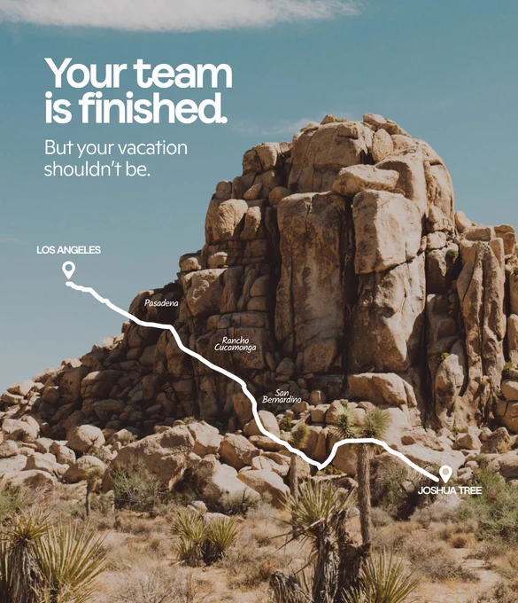 Desert rocks and sparse plants in Joshua Tree with a white route map from Los Angeles overlaid. Text reads: “Your team is finished. But your vacation shouldn’t be.”