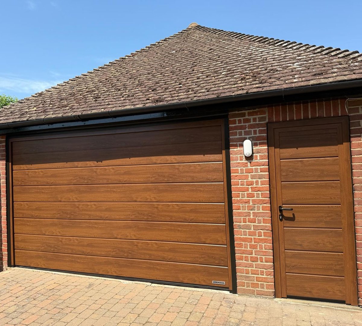 easterngroupuk's tweet photo. A lovely upgrade completed in Bishop’s Stortford. We installed a matching Hörmann M‑rib #SectionalGarageDoor and #SideDoor in Dark Oak complete with a coordinated frame. The whole setup looks fantastic - perfectly matched. Always great to help homeowners bring a fresh look! https://t.co/acaaapHzhj