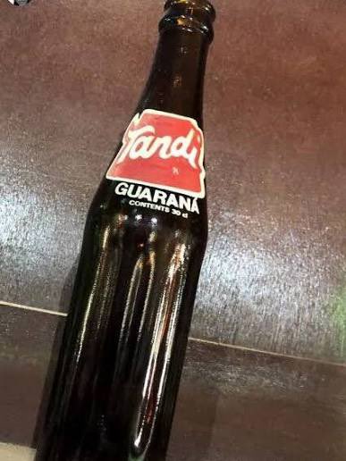 nwoko_greg62705's tweet photo. This drink came to Naija in the 1980s:

Guaraná is a heavily caffeinated beverage native to the Amazon Basin and is deeply intertwined with Brazilian culture. 

Historically, indigenous communities like the Sateré-Mawé harvested the plant's seeds, pounding them into a powder to create a stimulating energy paste and tea

Tandi Guarana arrived in Nigeria in the early 1980s. 

Originally from Brazil, the fruity, caffeinated soda became a cultural staple throughout the 1980s and 1990s before it was eventually phased out of the mainstream Nigerian market by the late 1990s.

It was bottled locally by Coastal Bottlers Ltd in Amuwo-Odofin, Lagos.