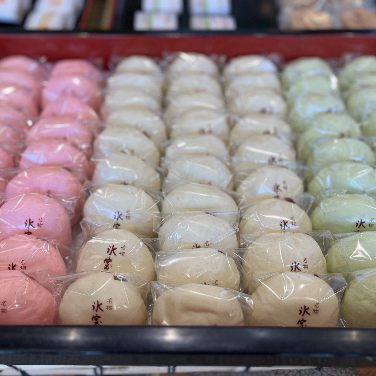wagashibuyer's tweet photo. #菓子案内

最後に金沢駅の西側に向かって、横浜高島屋の2月のイベントに参戦している #つば屋 さんへ。ちょこっと秋の話をしにいきました。

#氷室饅頭 はブームとかそんなものではない。金沢では、生活の中に浸透した夏の風物詩であって、独自の歳時記のお菓子なのです。まあ、県外の僕たちには信じられないくらいのお饅頭が売れていきます。当たり前ですが、和菓子屋さんはみんな疲労困憊。

家族でお店を営んでいるつば屋さんの若旦那によると、6/30は午前0時から製造に入って、7時には4千個あまりをスーパーに納品し、そのあと会社🏢や学校🏫の特注を次々にこなして、一日で1万個くらい蒸しあげるという。それだけ根づいているお菓子はあまりないのです。

若旦那は最終日の7/1全ての氷室饅頭を見送ると、そのまま朦朧として、7/2は爆睡するしかない。我々と会ったあと、もう寝ます💤という。まさに氷室饅頭は決戦なのです。