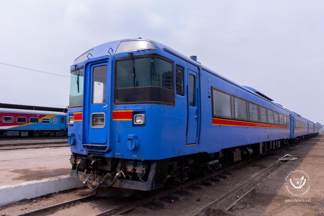 Presidence_RDC's tweet photo. Après près de 15 ans d'inactivité, les rails de la capitale reprennent vie. Ce 30 juin, le Chef de l'État Félix Tshisekedi a effectué le trajet reliant la Gare centrale à l'aéroport de N'djili.

La relance de cette ligne de 25 kilomètres vient relever d'importants défis structurels pour la ville de Kinshasa notamment le désengorgement du trafic routier face aux embouteillages de la capitale, l'amélioration du pouvoir d’achat par une offre tarifaire stable et accessible, ainsi que la restauration du domaine public à travers la libération des emprises ferroviaires occupées illégalement.

Pour le Chef de l'État, le trafic ferroviaire devrait également s'étendre à la partie Ouest de la capitale, entre la Gare centrale et la place Kintambo Magasin. Après ce trajet inaugural, le trafic quotidien pourrait reprendre dans moins de trois semaines. L’objectif est de réduire de 20 à 30 minutes la durée du trajet entre la Gare centrale et l’aéroport international de N’djili.
https://t.co/YPVzlxpWez