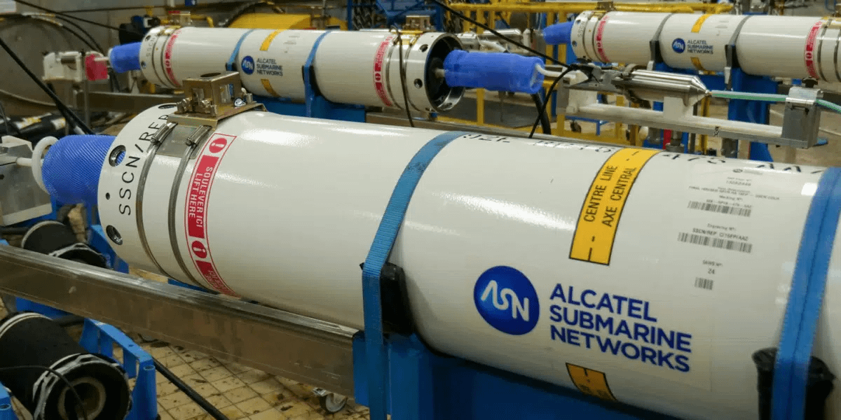 Gaurab's tweet photo. Even Amazon cannot get a new submarine cable for its AI data centers before 2028. SubCom alone holds $4.7 billion in unfilled orders. That's the longest backlog in the industry's history. Every AI model trains on data stored across oceans, data that crosses the seafloor on a fiber optic cable. One component has to work without maintenance for 25 years on the ocean floor: The repeater. It amplifies light using erbium-doped fiber pumped by lasers rated for 200,000 hours of continuous operation. Repeaters sit at depths of 8,000 meters under 800 atmospheres of pressure, spaced every 70 km along cables stretching 15,000 km. A single transpacific cable contains up to 200 repeaters. Once deployed, they can't be serviced. Only 4 companies on Earth can build a complete submarine cable system.