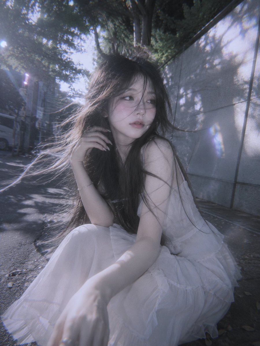 saniaspeaks_'s tweet photo. GPT image 2 via chatgpt 

Prompt:
A surreal doll-like young woman with waist-length flowing hair, captured in a realistic candid portrait with a soft everyday charm. She appears shy yet connected with the camera, gently feeling the breeze as strands of hair move naturally around her face. Ethereal beauty with porcelain-cool skin, a delicate oval face, pointed chin, and fair complexion. Shot in a spontaneous snapshot style with a slightly tilted frame, low-angle perspective, and ultra-wide lens for a dynamic composition. Soft white pastel tones mixed with subtle silver hues, cinematic side lighting outlining her silhouette, translucent light leaks, and dreamy overlays create a nostalgic atmosphere. Inspired by Japanese summer aesthetics, featuring dappled tree shadows, gentle motion blur, soft grain, faded contrast, cool indigo undertones, expired film colors, low saturation, natural makeup, delicate clothing textures, and an artistic, cinematic film look with a dreamy and expressive mood.