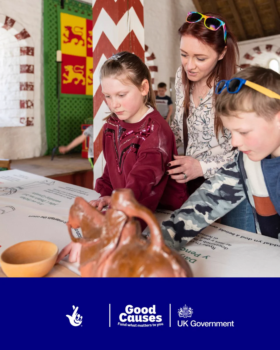 A woman and two children looking at heritage objects on a museum table
