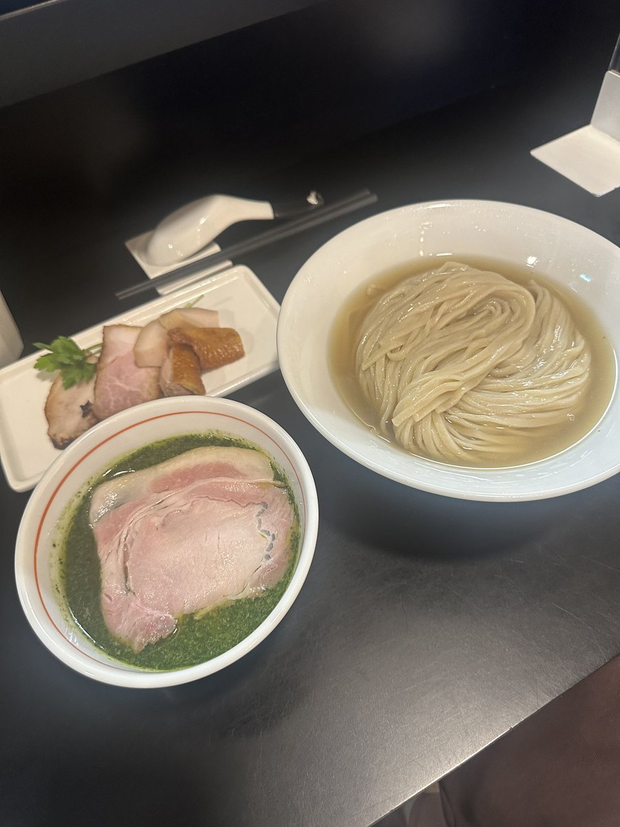 senjusan's tweet photo. らぁ麺飛鶏
地鶏・菰錦豚・貝・節・ハーブのつけそば大盛鶏増し豚増し
この日は京都の麺友斬人さんに誘われ鶏撃〜🐔🐔🐔💨
まあ誘われなくても行くんだけどね😏笑
待ち時間から今日は揃って白湯食べようか？なんて話してたが蓋を開けてみればふたりとも限定というお決まりのオチに🫣笑
名前からかなり期待できそうな匂いがプンプンしていましたが着丼すると圧巻のビジュアルに驚きを隠せない😳
白醤油ベースに動物の旨味が重なりきっとこれだけでもかなり美味しいだろうにと思うところにダメ押しの🌿がドーン🤗
バジルに紫蘇とイタパセを加えたという鮮やかな緑色のハーブは爽やかなスパイシーな香りと苦味や甘味も伴った清涼感を醸し出し食欲を増進させる🤤
麺側には複数の貝と節でとったお出汁がたっぷりと張られており麺のポテンシャルを引き立てる🤭
どういう構成か聞くの忘れたがこの出汁めちゃくちゃ美味くてこのまま冷かけで食べてしまいたかったのは内緒だが🤫笑
麺はいつも通り口あたり滑らかな喉越しともっちりとした食感の良さが秀逸😋
上質な鶏豚トッピングのクオリティは言わずもがなスープと麺そしてお出汁や具材までもが一体感ある見事な仕上がりで非の打ち所がないとはまさにこの事だな🤭
多種多様な素材の特徴を把握し完璧に調和させた長谷川さんらしい創造性に富んだ魅惑の逸杯はやっぱり今日も控えめに言って宇宙一でした😂