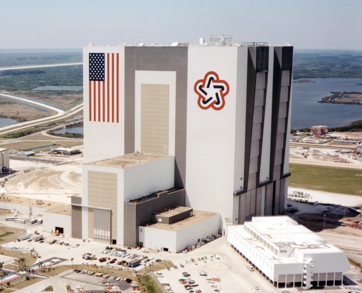 Aerial view of the Vehicle Assembly Building at NASA's Kennedy Space Center in 1977. The massive flag and bicentennial logo were painted on its side in 1976 as part of the celebrations for the nation's 200th birthday. Credit: NASA