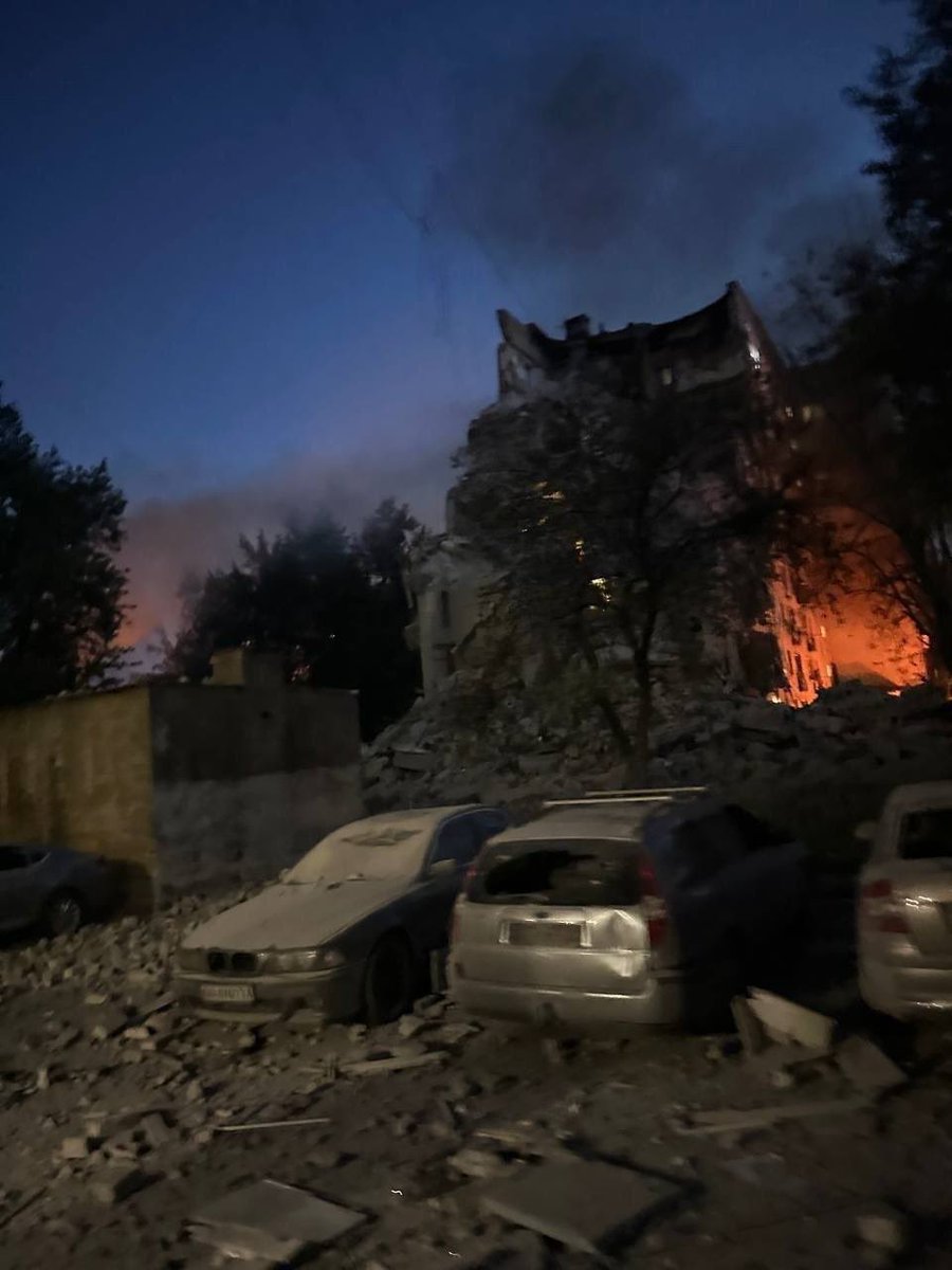hopeforukraine's tweet photo. Kyiv. Not a military target — an apartment building. Someone’s kitchen. Someone’s bedroom. Roof gone, walls split, fire still burning. Cars crushed below where families parked and went upstairs like every other night. This is deliberate. This is terror. https://t.co/XLqfS1lrxh