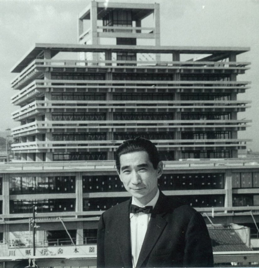 yutani_LAN's tweet photo. 丹下健三、香川県庁舎で「民主主義ごっこ」を本気でやった話

1958年竣工の香川県庁舎は、単なる建築ではない。
知事・金子正則という一人の「プロデューサー気質のオッサン」が、丹下健三という天才に本気で理想をぶつけた結果生まれた、戦後民主主義の実験場である。

丹下は当初、市民のための開かれた空間を構想していたが、驚くべきことに屋上を市民に一般開放するというアイデアは丹下の設計になかった。これは金子知事の「たっての希望」だったというのだから面白い。

建築家の理想主義だけでは足りず、政治家の「これは市民に開放しなきゃダメだろ」という一声があって初めて、民主主義は空間として完成した。
政治家と設計者たちがガチで戦後民主主義を信じていた証拠だ。

さらに、金子知事は戦争で夫を亡くした女性たちを清掃員として積極的に雇用した。
多くの人が利用していたが、彼女たちが心を込めて庁舎を磨き続けたことで、建物は常に清潔に保たれ、結果として職員のモチベーションまで底上げされたと記録にある。
つまりこの庁舎が半世紀以上も「生きた名建築」でいられたのは、コンクリートの美しさだけの話ではない。
権威的な庁舎ではなく市民に開かれた場所にするという政治的意志と、それを日々磨き続けた無名の人々の労働があって、初めて建築は理念を保ち続けられる。理想は放っておくと朽ちる。メンテナンスされて初めて、理想は生き延びる。

今の香川県の知事と議員の皆さん。あなたたちがいるその建物に込められた想いをちゃんと理解してますか？