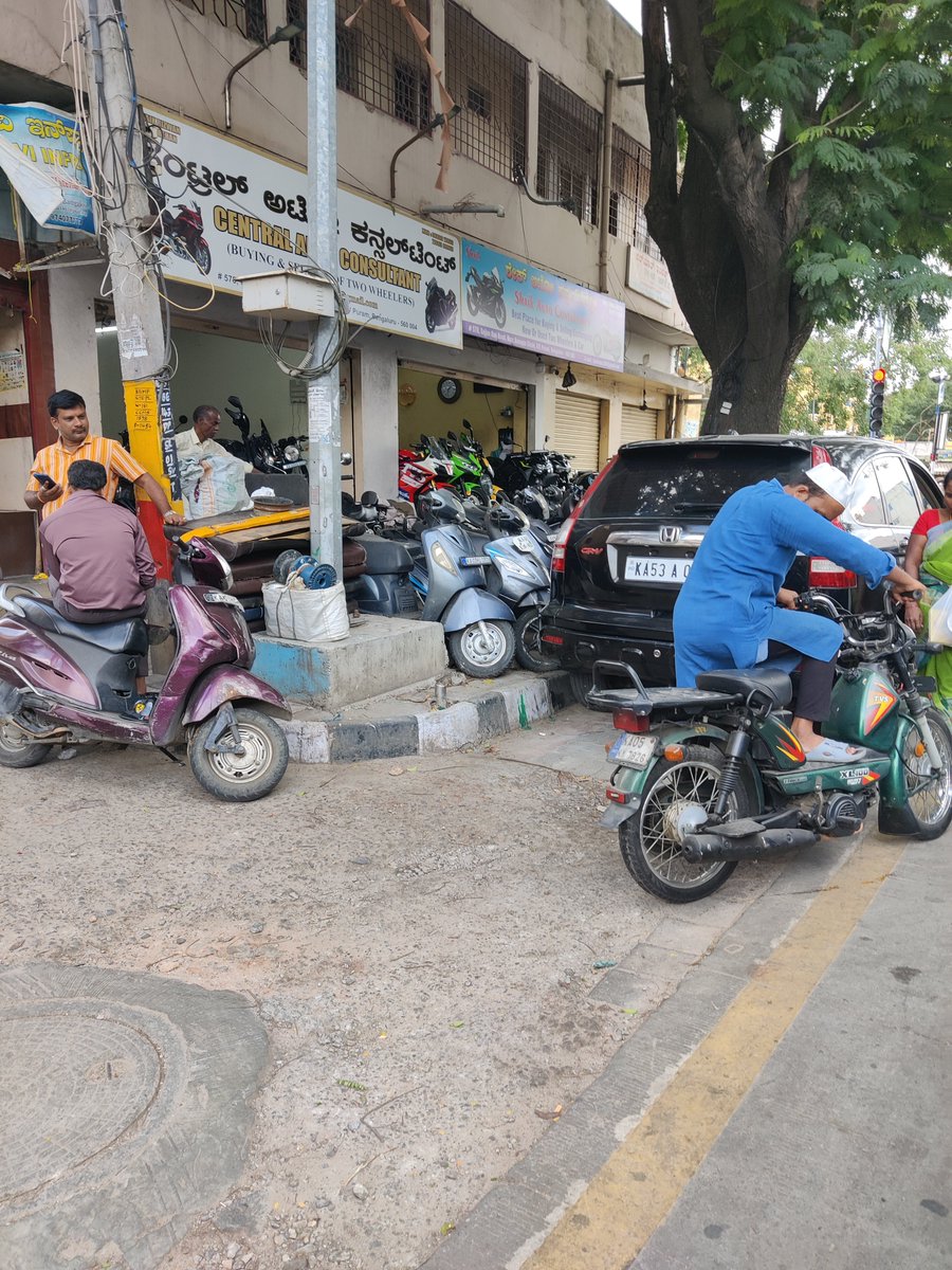 CDilip0510's tweet photo. @krishnabgowda 
Sajjanroa VV Puram where. Footpath is complete enchored by ressler of 2 wheeler shop when you are removing small street seller why you can't clear this they had completed occupied no able use footpath . https://t.co/e0Np6ougBu