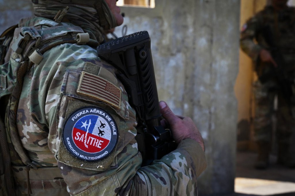 LatrincheraCL's tweet photo. Infantería de Aviación de la FACh y Security Forces de la USAF entrenan operaciones de combate urbano en Salitre 2026

Como parte del programa de actividades del Ejercicio Multidominio Salitre 2026, efectivos de la Infantería de Aviación de la Fuerza Aérea de Chile y de las Security Forces de la Fuerza Aérea de Estados Unidos desarrollaron un entrenamiento conjunto orientado a perfeccionar las capacidades de protección de la fuerza y fortalecer la interoperabilidad entre ambas instituciones. La información fue difundida por el Centro de Prensa de Salitre 2026.

La jornada contempló ejercicios de Military Operations in Urban Terrain (MOUT) y Close Quarters Battle (CQB), disciplinas enfocadas en operaciones militares en ambientes urbanos y combate en espacios confinados. El entrenamiento incluyó el empleo de vehículos de infantería mecanizada y la ejecución de escenarios que simularon amenazas en zonas urbanizadas.

Durante la actividad, el personal de ambas fuerzas intercambió tácticas, técnicas y procedimientos relacionados con el ingreso a edificaciones, despeje de recintos y desplazamiento en áreas reducidas. Posteriormente, los participantes conformaron patrullas mixtas para ejecutar ejercicios integrados bajo procedimientos comunes.

Según informó el Centro de Prensa de Salitre 2026, este entrenamiento permitió evaluar la compatibilidad de los procedimientos operacionales y reforzar la capacidad de actuación conjunta entre las fuerzas participantes, en línea con los estándares OTAN empleados durante el ejercicio.

Las actividades forman parte del componente terrestre de Salitre 2026, que complementa las operaciones aéreas mediante la integración de capacidades de protección de la fuerza, combate urbano y coordinación multinacional, fortaleciendo la preparación para operar en escenarios multidominio.

José Opazo - Centro de Prensa Salitre 2026