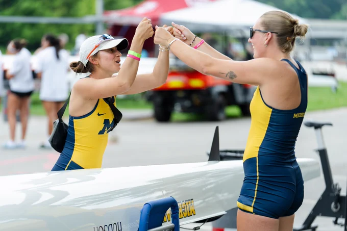 Two Michigan rowers fist bumping as they warm up