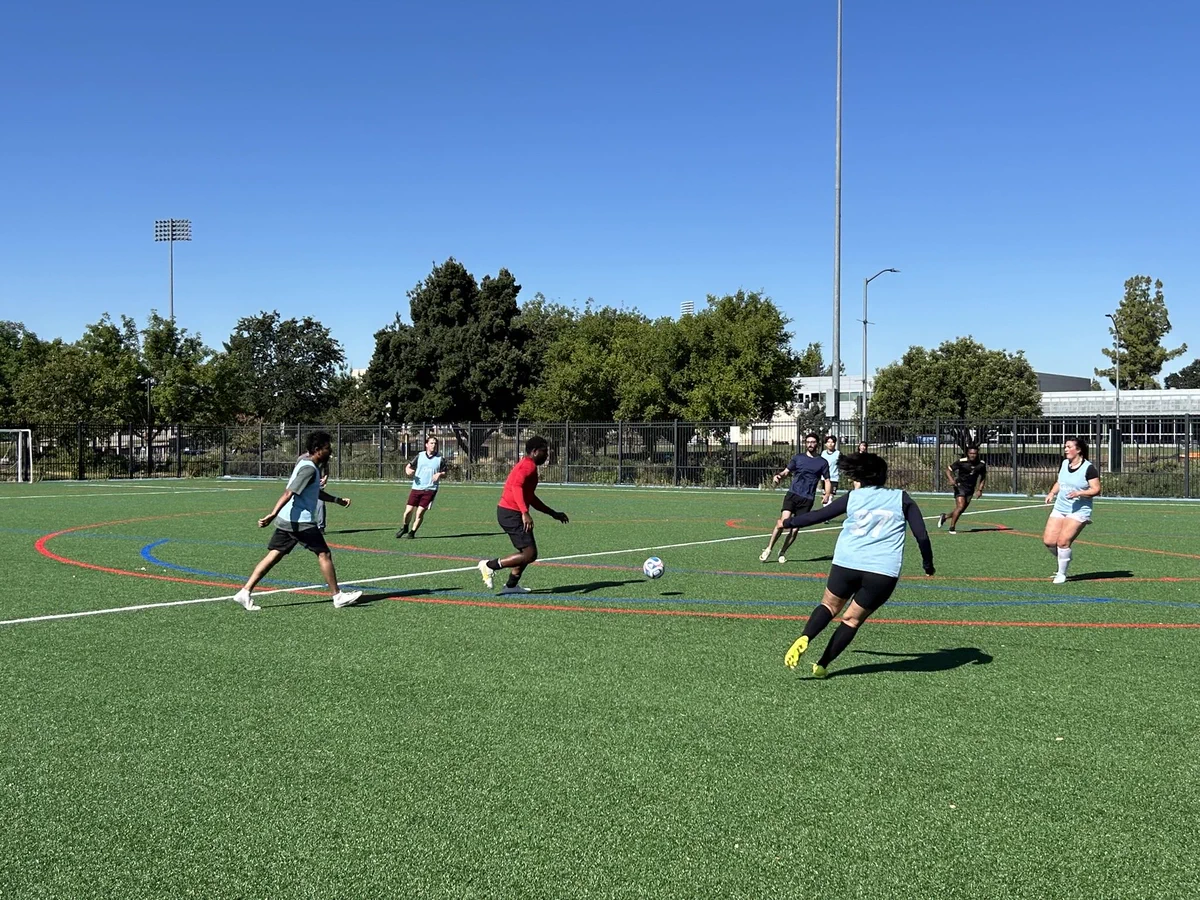 Grad students on field running as they play soccer.