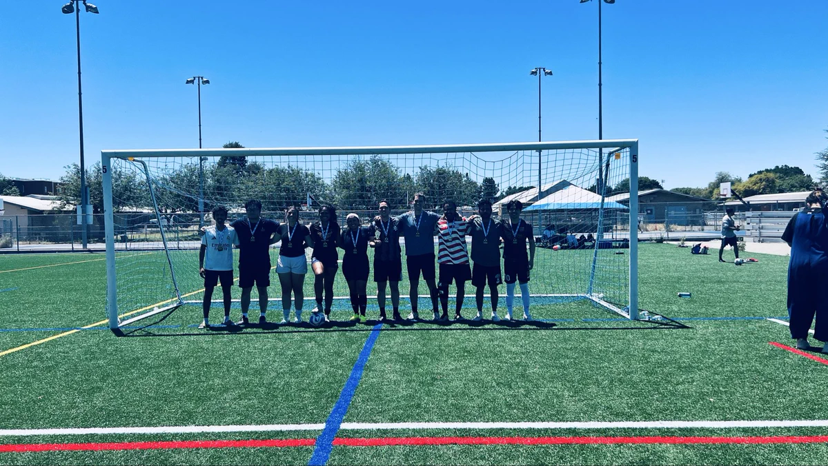 Grad students on soccer field smiling together under goal post.