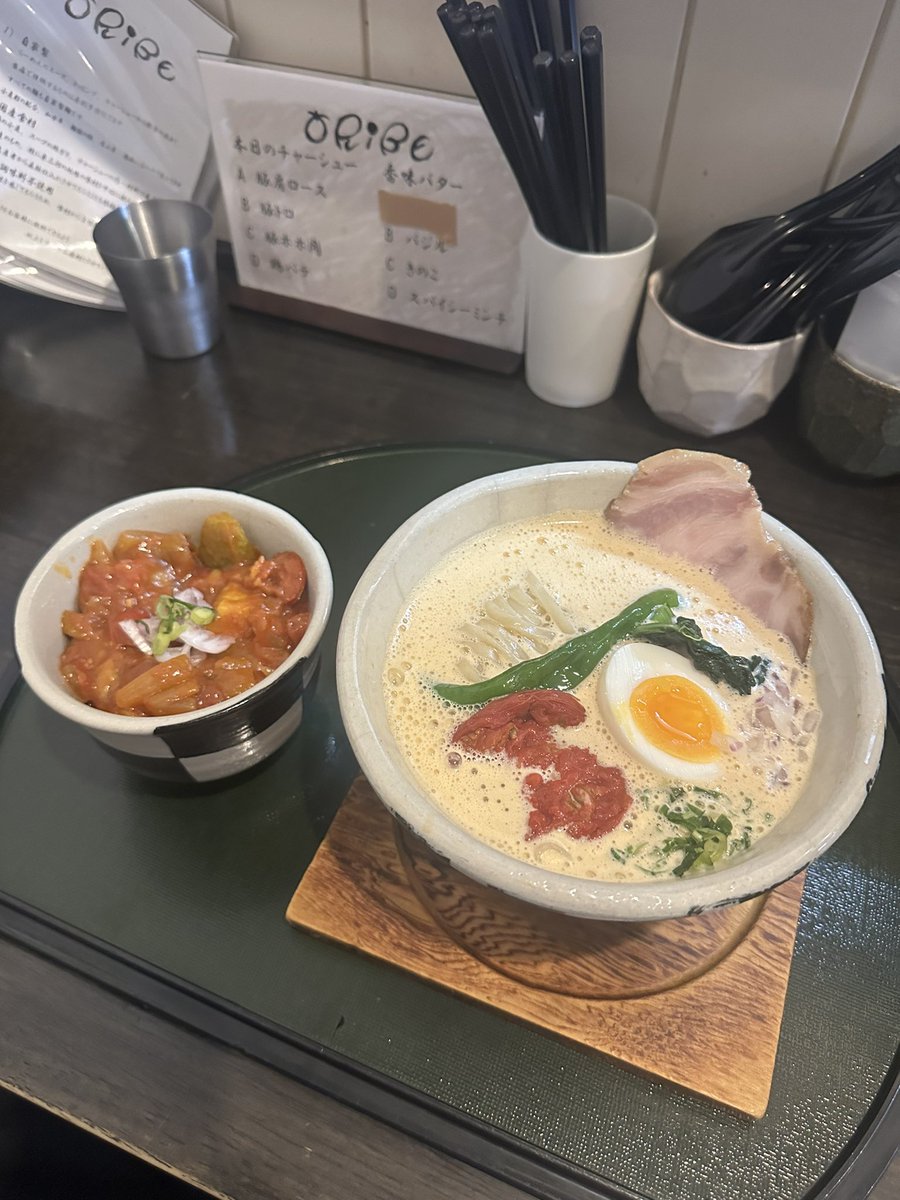 senjusan's tweet photo. ORIBE
白湯麺ver.4.7改番外編
~泡・まるごと甘海老~
月、水は行くお店が固定されてるんだけどお気に入りのお店は火曜日休みが多く毎週悩ましいところでしたが先週に引き続きORIBEさんへポールで突撃💨
つけ麺とめっちゃ迷ったが白湯麺をチョイス🫣
そのまんま甘海老の風味と旨味が全体を包み込むような白湯スープは程よい濃度ときめ細かい泡の優しいアプローチが堪らない🤤
ローストトマト🍅が刻むアクセントも👍
滑らかな舌触りと弾むような弾力が心地いい平打ち麺はスープによく馴染み相性も良き✨
三浦店主から先週の麺と違いますがどうですか？と声をかけて頂きましたがちょっと食感が違うけど全然美味しいですよ😋
そもそも麺が美味しいお店しか行かないので安心してください🤭
そして人生初となるラタトゥイユ丼を頂きましたが今が旬の夏野菜をふんだんに使用したニースの郷土料理だけあり今までに食べたことない風味が凄く新鮮☺️
夏野菜をオリーブオイルで炒めトマトを加えて煮込んであるので爽やかな清涼感が広がり奥行きのある味わいがクセになりそう😚
甘海老白湯とのマッチングも最高だしめちゃくちゃ美味かった🤣
ORIBEさんは限定メニューが豊富だしハンター予備軍には重宝するのね〜😂