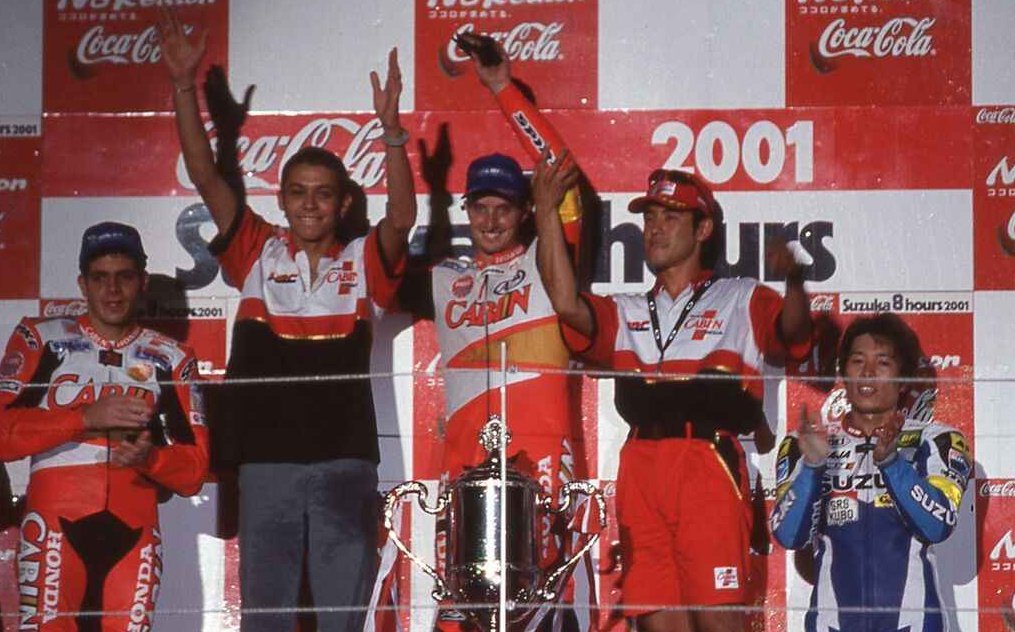 LambeResing's tweet photo. Dibalik kesuksesan Valentino Rossi sebagai GOAT di dunia motorsport, sebenarnya ada satu kemenangan dari event besar yang diraihnya tapi jarang dibahas, dan bahkan ia sendiri kapok buat ikut lagi.

Event tersebut adalah Suzuka 8 Hours.

Valentino Rossi di masa mudanya terobsesi dengan dunia otomotif Jepang dan dunia motorsport di sana. Bahkan ia sendiri memasang nickname "Rossifumi" karena mengidolakan rider asal Jepang, Norifumi Abe.

Ada satu ajang yang menarik perhatian Vale muda, Suzuka 8 Hours. Vale pun meminta sendiri ke Honda kesempatan tampil di Suzuka 8 Hours, saat negosiasi kontraknya dengan Honda.

Semua sudah disiapkan untuk Suzuka 8 Hours 2000, Vale turun dengan Honda VTR1000SPW, dan berpasangan dengan rider top di kategorinya, Colin Edwards, yang jadi pemenang di 1996 dan nantinya menjadi juara dunia di WSBK.

Ketika race dimulai, cerita pahit bermula. Vale muda masih kaget. Begitu Edwards kasih gap aman, giliran dia turun malah crash. Motor sempat diperbaiki, sialnya Edwards ikutan crash yang berakhir DNF.

"Be careful what you wish for" benar-benar menimpa Valentino Rossi muda. Masalahnya kesepakatan yang berawal dari "minta jatah" berubah jadi sebuah tuntutan, yang bikin dia mau gak mau wajib menang jika ingin lepas dari kesepakatan tersebut.

Di era itu bukan hal yang langka jika ada rider yang dikontrak oleh suatu pabrikan untuk turun dinas di Suzuka 8 Hours, karena event tersebut memang dianggap sangat penting bagi pabrikan sendiri. Tapi untuk kasus ini Vale muda yang minta.

Pada tahun 2001 Vale fokus dengan satu target, wajib menang. Persiapannya sudah lebih matang, dan Edwards sendiri pernah cerita betapa desperate-nya Vale saat itu buat bisa menang.

Race dimulai, drama persaingan juga terasa karena mereka harus melawan rival dari sesama Honda, Tadayuki Okada dan Alex Barros.

Untungnya rejeki berpihak ke mereka. Okada dan Barros sempat crash di awal race, dan blunder di pit stop terakhir. Rossi dan Edwards berhasil memanfaatkannya untuk raih kemenangan.

Namun kemenangan itu meninggalkan bekas. Rossi mengaku butuh berbulan-bulan untuk benar-benar pulih dari beban fisik balapan tersebut, dan merasa kapok untuk turun lagi di sana.

Perjalanan Vale di Suzuka 8 Hours juga membuatnya jadi bestie sama Colin Edwards, yang pernah meng-carry dia sebagai rider yang lebih berpengalaman saat itu. Uniknya beberapa tahun kemudian mereka menjadi rekan setim di Yamaha pada musim 2005-2007.

Sebuah cerita kesuksesan yang pemenangnya jarang ngebahas gara-gara udah kapok ikutan 😅