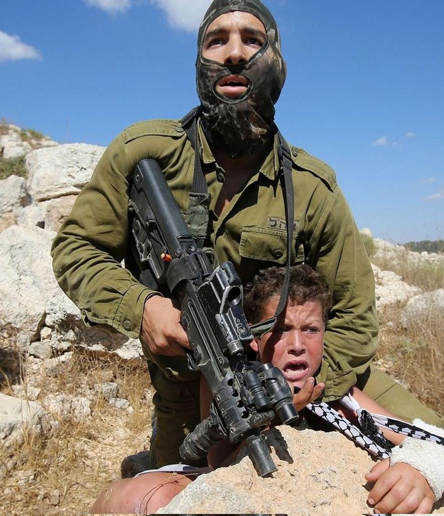 Yamani_Military's tweet photo. Israeli soldier attempting to 
 Kidnapping 12-year-old Palestinian child who has a broken arm (2015 https://t.co/pmZcVt4Uz8