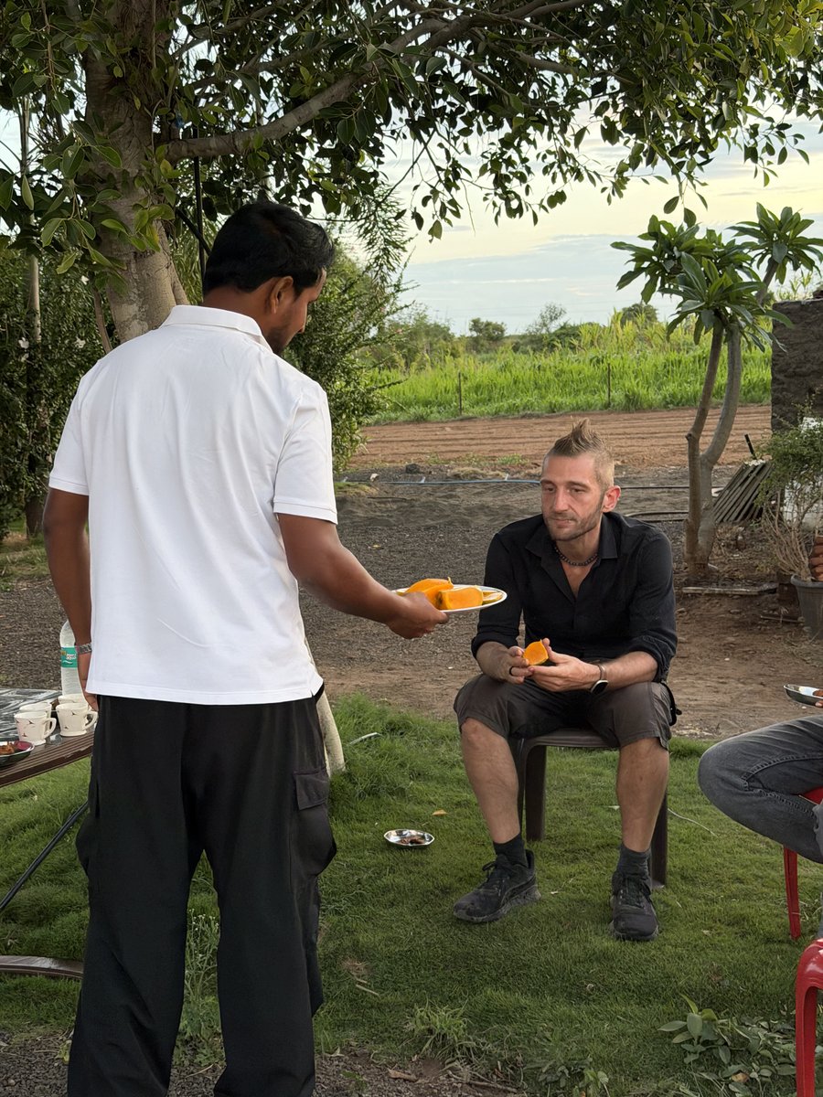 IndianFarmer_'s tweet photo. खरं नातं हे कॉन्ट्रॅक्टमुळे तयार होत नाही, तर वर्षानुवर्षांच्या विश्वासामुळे तयार होतं!

२०१९ मध्ये Plantix सोबत पहिल्यांदा काम सुरू केलं. तेव्हा कुणालाच कल्पना नव्हती की एका मोबाईल ॲपच्या मार्केटिंगपासून सुरू झालेला हा प्रवास एक दिवस त्यांच्या को-फाउंडरना माझ्या शेतापर्यंत घेऊन येईल.

मध्यंतरी कामानिमित्त 2-3 वेळा भारतातल्या इंदोरमधल्या त्यांच्या ऑफिसमध्ये जाणं झालं. चर्चा झाल्या, मीटिंग्स झाल्या. पण मनात नेहमी एक इच्छा होती, "एकदा त्यांनीही माझं शेत पाहावं. इथली माती, इथले प्रयोग आणि शेतकऱ्यांचं खरं जग अनुभवावं."

आणि तो क्षण अचानक आला.

तर सहजच मी दुपारी ट्रॅक्टरवर स्प्रे करत होतो. इतक्यात आकाशचा फोन आला, "रॉब आपल्या भागात आहेत." आधी विश्वासच बसला नाही. मग लगेच फोन, मेसेज केले आणि संध्याकाळी ते खरंच माझ्या गावात आले. मग पुढचे दोन तास आम्ही फक्त शेतात फिरलो.
त्यांना क्रिमसन व्हरायटीची द्राक्षबाग दाखवली. आलं, ऊस, मिरची, टोमॅटो दाखवले. सॉईल सेन्सरपासून ड्रिप इरिगेशनपर्यंत मी काय-काय करतोय, त्यात कोणत्या अडचणी येतात, कोणते डिसिजन्स घ्यावे लागतात या सगळ्यावर मनमोकळी चर्चा केली.

रॉब फक्त शेत बघत नव्हते तर ते प्रत्येक गोष्ट समजून घेत होते. प्रश्न विचारत होते. निरीक्षण करत होते. आणि तेव्हा मला पुन्हा जाणवलं, मोठ्या कंपन्या फक्त चांगलं प्रॉडक्ट बनवून मोठ्या होत नाहीत; तर त्या  जमिनीशी जोडलेल्या असल्यामुळे मोठ्या होतात.

मग शेवटी घरी आलो. गरमागरम भजी, चहा, आंबे, चिंचा यावर ताव मारत गप्पा सुरूच ठेवल्या. त्यांनी आमचं बेस लोकेशनही पाहिलं. इथूनच इंडियन फार्मरचे कोर्सेस तयार करतो, व्हिडिओ शूट करतो, शेतकऱ्यांपर्यंत नॉलेज पोहोचवतो हे पाहून त्यांनाही आनंद झाला.

दुपारी ट्रॅक्टरवर बसलेला मी आणि संध्याकाळी इंटरनॅटशनल कंपनीच्या को-फाउंडरसोबत माझ्या शेतात फिरणारा मी, या दोन क्षणांमध्ये फक्त एकच गोष्ट कॉमन होती आणि ती म्हणजे शेतीवरचा विश्वास.

मला वाटतं, आयुष्यात काही भेटी आपण ठरवत नाही. तर ते आपलं काम आणि त्याच्याशी असलेला प्रामाणिकपणा ठरवतं. आणि तेच सांगून जातं की योग्य काम करत राहिलं तर योग्य माणसं एक दिवस तुमच्यापर्यंत स्वतःहून येतात.

-संतोष जाधव (इंडियन फार्मर)