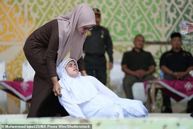TeamTrump47's tweet photo. 🚨 BARBARIC! First woman publicly caned in Indonesia’s Aceh under brutal Sharia law for kissing her partner on a TikTok livestream. 😡

She knelt screaming in agony as a masked officer whipped her back over and over. Her face twisted in pain until she passed out from the lashes.

Onlookers cheered “whip harder!” Police watched as she collapsed, clutching her back. Medics checked her but she still has to finish the 21 lashes when she recovers.

Her partner and others were caned too. All for a kiss on social media.

This is Sharia “justice” in 2026. Pure savagery. Where’s the global outrage? 🔥

Credit: Daily Mail