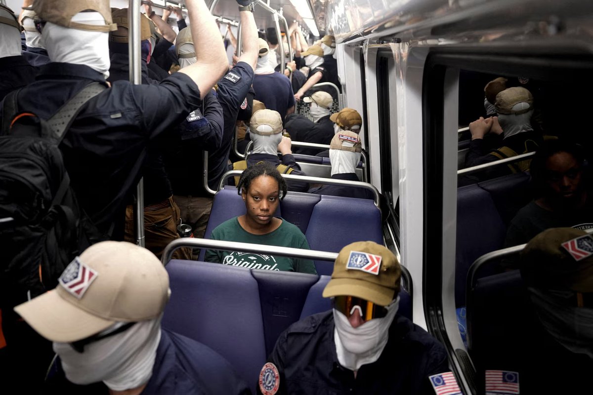 republiqueBRA's tweet photo. 📸 Foto registra mulher negra sentada no metrô, cercada por nacionalistas com máscaras brancas que marcharam por partes de Washington antes das festividades do Dia da Independência dos EUA. https://t.co/WiYKO3oTta