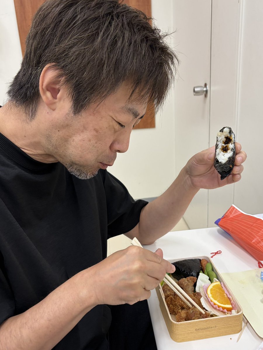 tmitzru's tweet photo. 広島といえばむさし。ベーシスト種子田さん、左手におにぎり、右手に唐揚げ！でご満悦。 https://t.co/dwvB6SLjRO