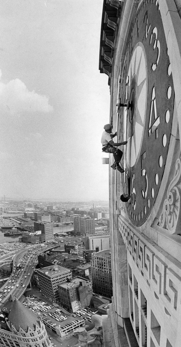 OldSchoolBoston's tweet photo. "The coolest spot in town, or at least one of the highest ones. John Otto Sr. + his son holding the ropes below, John J. of Dedham, paint the face of the biggest clock face in the United States at the Custom House, Boston. The clock is prepared for the bicentennial purpose. The Northeast Steeple + Tower Co. has been in business for 27 years" June 1976. (David L. Ryan Boston Globe)