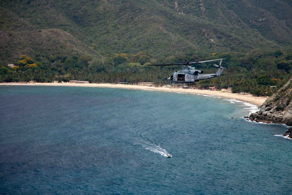 sentdefender's tweet photo. A U.S. Marine Corps UH-1Y Venom assigned to the “Blue Knights” of Marine Medium Tiltrotor Squadron 365 (VMM-365), Littoral Combat Force-24 (LCF-24), conducts site survey operations along the coastline of La Guaira, Venezuela, while supporting earthquake relief efforts led by the U.S. State Department.