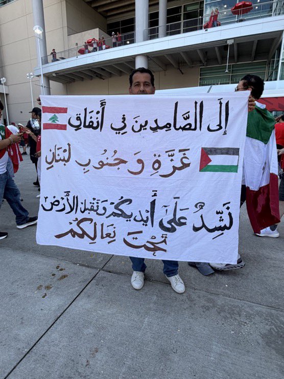 TheSaviour's tweet photo. 🇲🇦🇵🇸🇱🇧A Moroccan fan raised a banner at yesterday’s match, Morocco vs Canada, on which it was written:

"To those standing firm (steadfast) in the tunnels of Gaza and South Lebanon, we hold your hands and kiss the ground beneath your shoes." https://t.co/PI1x6XvakH