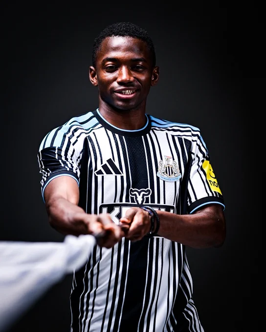 Bazoumana Touré pictured in our 2026/27 home shirt waving a flag. 