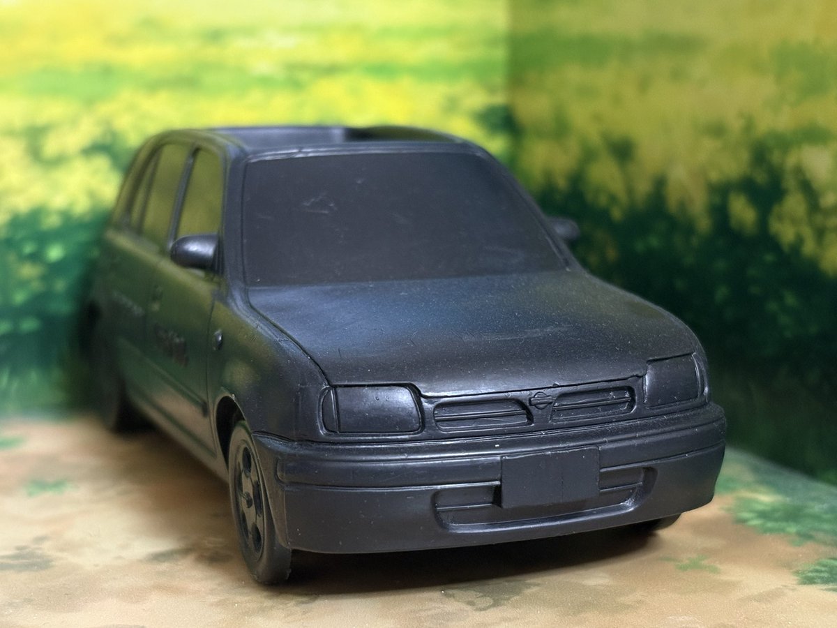 vz61_scorpion2's tweet photo. 小学生の頃、社会科見学で日産村山工場へ行った時にもらった、2代目日産マーチの小物入れ。

これは単なる記念品ではなく、日産というメーカーが当時どんな時代意識を持っていたのかが見える、なかなか面白いアイテムだと思う。

モチーフになっているのは、丸みを帯びた2代目マーチ。実車の愛嬌あるフォルムをそのまま簡略化しつつ、ドアや窓枠、バンパー、ホイールまでしっかり造形されている。黒一色の成形だから派手さはないが、逆にそれが工場見学の記念品らしい質実剛健な雰囲気を出している。

側面には「NISSAN」と「リサイクル」の文字。バンパーの樹脂を再利用して作られたものらしく、ただの販促グッズではなく、リサイクルや環境への取り組みを子どもにも分かりやすく伝える教材のような存在だったのだろう。

今見ると、2代目マーチの実車そのものよりも、この小物入れに刻まれた時代の空気が渋い。村山工場、社会科見学、日産のものづくり、そしてリサイクルというテーマ。小さな黒いマーチの中に、当時の日産の姿勢が詰まっている。

ミニカーとは違うが、これはこれで立派な自動車文化の記録。手元に残っているだけで価値のある一品だと思う。