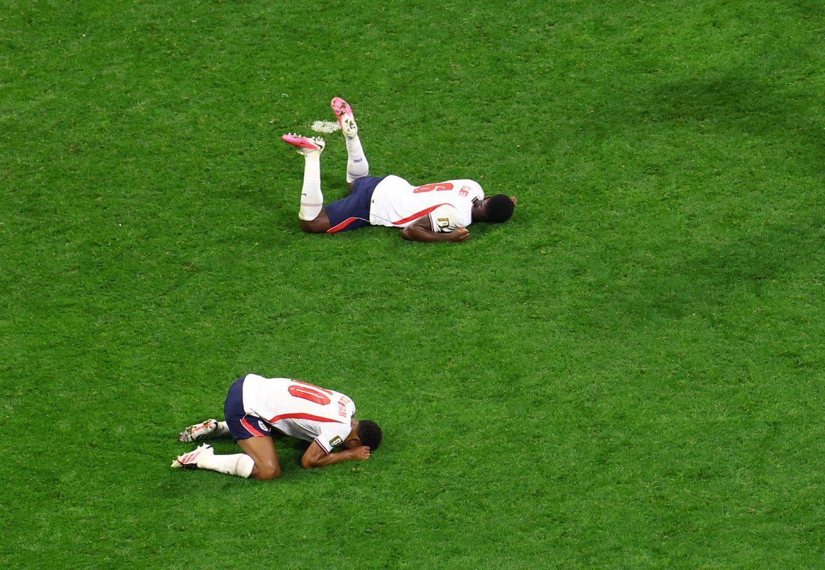 _TomClarke's tweet photo. WHAT a picture this is by Henry Romero of Reuters

Jude Bellingham and Marc Guehi absolutely finished at full time. An incredible effort https://t.co/oS9dxvGsYe