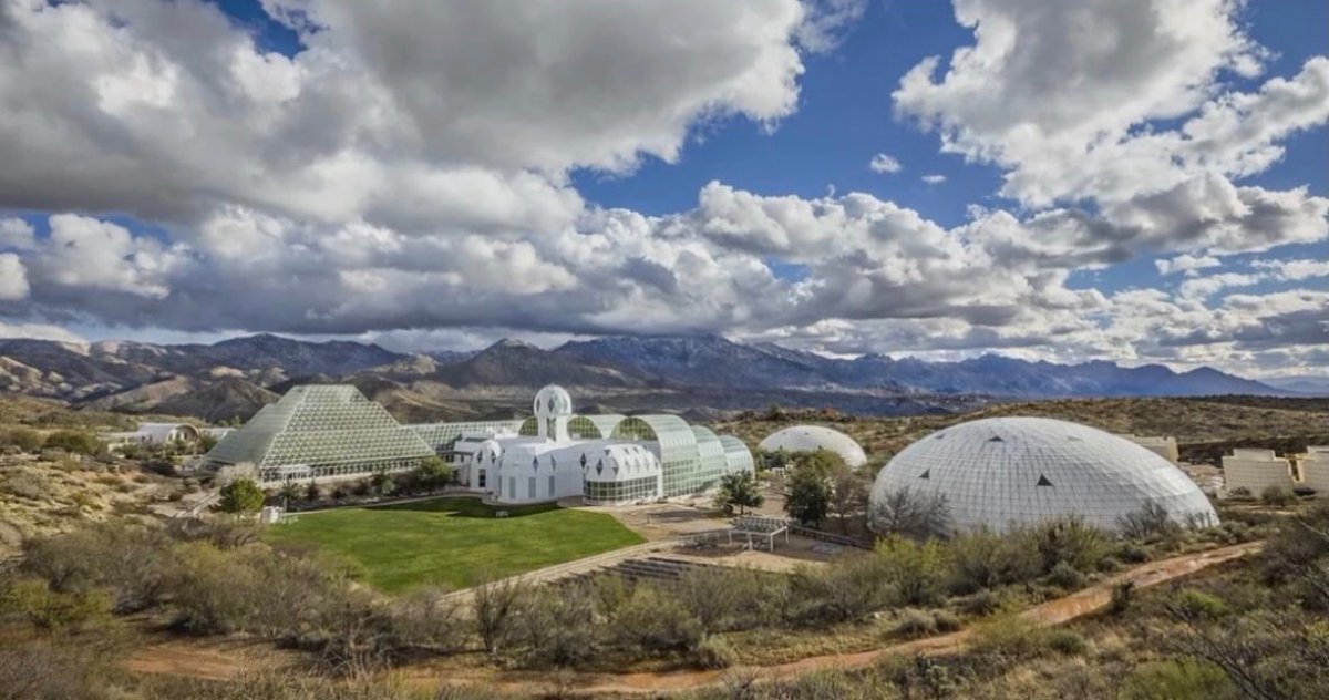 historyinmemes's tweet photo. In 1991, eight people sealed themselves inside an artificial, self-contained ecosystem in Arizona as part of an ambitious experiment to live without outside support. Over the next 16 months, oxygen levels fell from 21% to just 14% after carbon dioxide unexpectedly reacted with and became trapped in the facility’s concrete, disrupting the carefully balanced atmosphere.

The experiment was known as Biosphere 2, a huge glass-and-steel facility built near Oracle, Arizona, to test whether people could survive in a completely sealed ecosystem. Designed as a miniature version of Earth, it contained a rainforest, ocean, desert, wetlands, farmland, and living quarters. On September 26, 1991, eight crew members entered the enclosed habitat for a planned two-year mission.

The project was promoted as a step toward future space colonies and self-sustaining living, but it soon faced major challenges. Crops produced less food than expected, the crew lost weight, interpersonal tensions grew, and oxygen levels steadily declined. Researchers later discovered that soil microbes were consuming oxygen while producing carbon dioxide, much of which reacted with the concrete walls and became trapped as calcium carbonate. As a result, oxygen disappeared without a corresponding buildup of carbon dioxide, forcing the team to pump oxygen into the habitat to complete the mission.

Today, Biosphere 2 remains in operation and is owned by the University of Arizona, where it serves as a research center for climate science, Earth systems, and environmental studies.