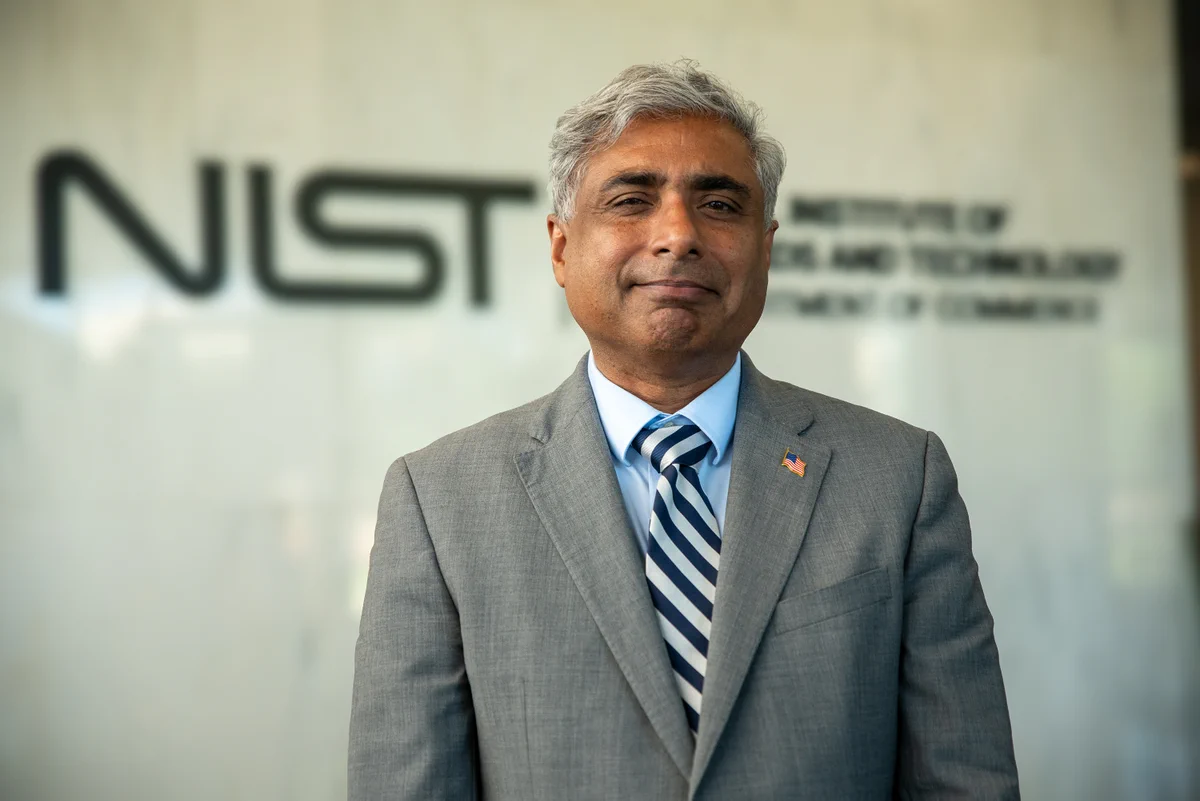 NIST director standing in front of the NIST logo