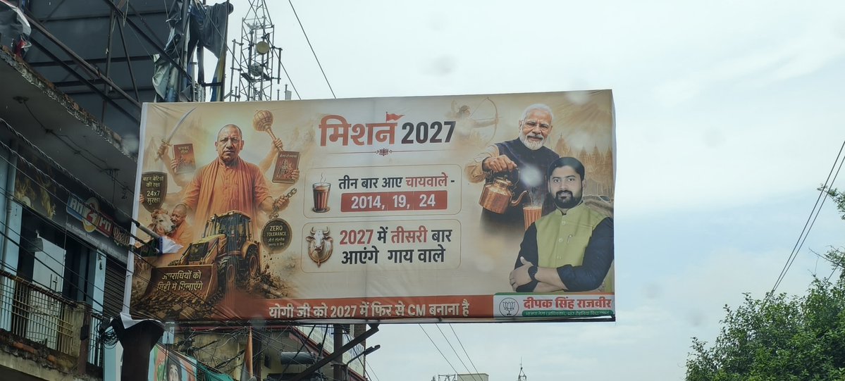 Chandanup65's tweet photo. "3 बार चाय वाले, 27 में गाय वाले"

प्रधानमंत्री नरेंद्र मोदी के संसदीय क्षेत्र वाराणसी स्थित सर्किट हाउस और सुसवाही में लगा अजीबोगरीब पोस्टर 
उत्तर प्रदेश में होने वाले 2027 के विधानसभा चुनाव के मद्देनजर यह बोर्ड यूपी के मुख्यमंत्री योगी आदित्यनाथ को तीसरी बार मुख्यमंत्री बनाने का दावा पेश कर रही है। तस्बीर में 2027 मे तीसरी बार आएंगे गाय वाले दिखाया गया है.!
वाराणसी के पोस्टर को देखकर चुनावी माहौल शुरू हुआ लगता है।