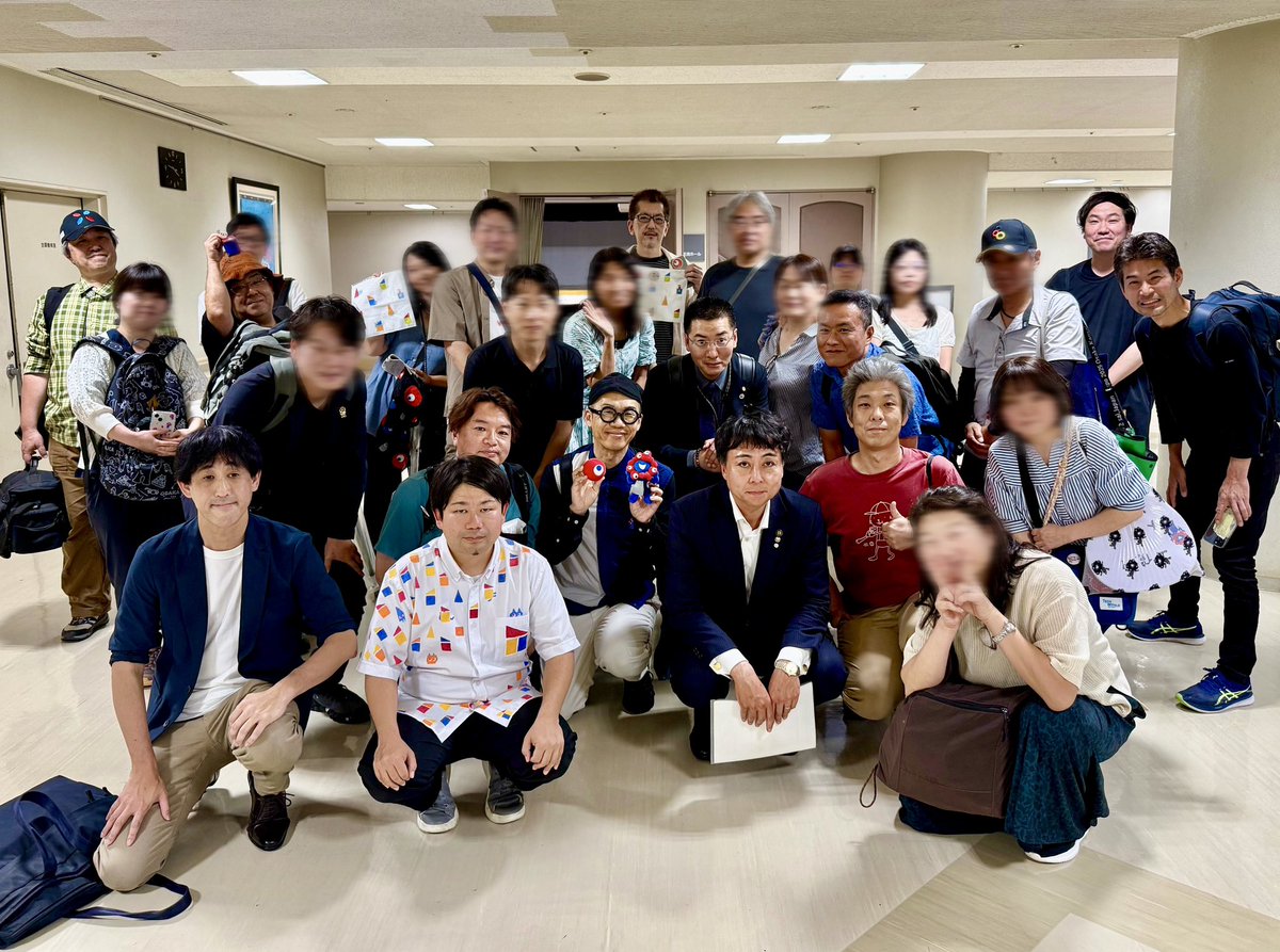 yonezawatakashi's tweet photo. 「ゴミリング」「ミャクミャクは気持ち悪い」発言など、万博批判の急先鋒だった山本けい交野市長が、万博を愛する人々に囲まれて写真撮影している。
みんな笑顔だ。

世界は平和になれる！

もちろん、過去の失言を容認できるわけでも、山本市長の肩を持つわけでもないが、

万博民が多く集まることが予測される公開対談を、特段の制限を設けずに開催し、ヤジが飛んだり吊し上げに遭ったりする可能性もあるなかで登壇されたことには、敬意を表したい。

#大阪関西万博　#EXPO2025
