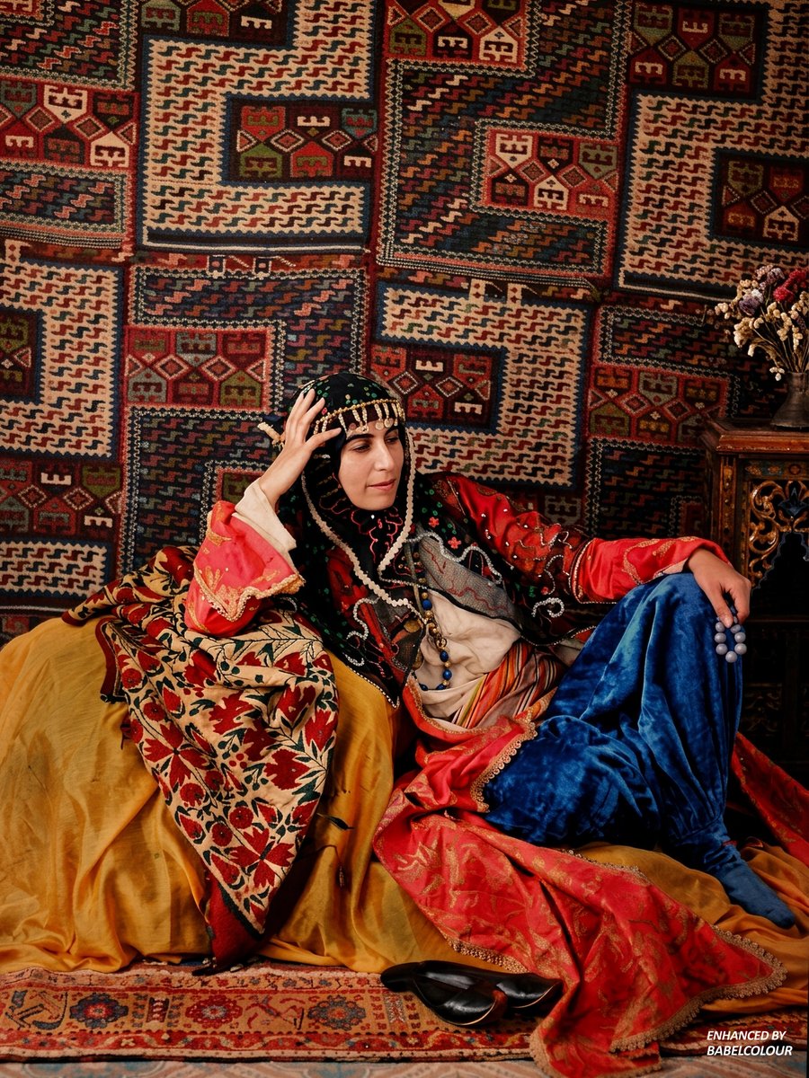 StuartHumphryes's tweet photo. Let me transport you back 116 years with this stunning Autochrome from 1910. I have cleaned-up this exquisite study of a woman clad in silks and velvets, posed against a backdrop of geometric kilim textiles, creating an enveloping riot of colour & texture & fabrics, which really draws us into every detail. The photographer's identity has not been recorded, though it is perhaps reminiscent of some of Gervais-Courtellemont's Syrian Autochromes. It was taken using an early colour glass-plate process and isn't colourised.