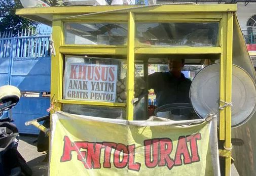 resahnegeri's tweet photo. Jujur... Kalau saya lihat tulisan "Anak Yatim Gratis" di gerobak makanan, pikiran pertama saya pasti promosi.
Biar orang berhenti. Biar dagangannya viral. Saya pikir begitu. Sampai beberapa waktu lalu saya benar-benar mampir ke gerobak yang memasang tulisan itu.

Waktu itu pembelinya lumayan ramai. Anak sekolah. Driver ojol. Pegawai yang baru pulang kerja.
Di depan sebuah minimarket di Jalan Kedinding Lor No 98, Kenjeran, Surabaya. Di gerobak pentolnya tertempel tulisan 'Khusus Anak Yatim Gratis Pentol'.
Saya baca dua kali. Masih nggak percaya.
Pas pembeli mulai sepi, saya iseng nanya.
"Pak."
"Emang sering ada yang gratisan?"
Beliau senyum.
"Iya."
"Nggak takut dimanfaatin orang?"

Beliau cuma ketawa kecil. "Kalau ada yang bohong..."
"Ya itu urusan dia."
"Lagipula... Saya nggak pernah merasa rugi mas. Alhamdulillah justru saya selalu merasa kecukupan. Masih bisa memenuhi kebutuhan keluarga, untuk membayar tanggungan, dan lainnya."
Jawabannya pendek. Tapi entah kenapa saya jadi malu sendiri.

Nggak lama kemudian... Datang dua anak. Masih pakai seragam mengaji. Yang satu langsung berdiri di depan gerobak. Yang satu lagi malah narik lengan temannya.
"Udah... malu."
Suara mereka pelan. Tapi saya dengar.
Bapak itu pura-pura nggak dengar. Beliau malah nanya,
"Mau pedas apa nggak?"
Dua-duanya saling lihat. Nggak ada yang jawab. Akhirnya yang paling kecil ngomong pelan.
"Pak..."
"Saya boleh yang gratis?"

Saya refleks nengok. Anak sekecil itu ngomongnya pelan sekali. Kayak takut ditolak. Bapak itu langsung ambil mangkuk.
"Nggak cuma boleh."
"Hari ini dapat bakso lebih." Beliau nambahin dua butir lagi. Tanpa ditimbang.
Anak itu langsung buru-buru bilang,
"Nggak usah banyak, Pak."
Saya kira karena malu. Ternyata bukan. Dia bilang,
"Nanti adik saya nggak kebagian."
Kalimat itu... Entah kenapa langsung bikin suasana jadi sepi.
Bapak itu berhenti ngaduk kuah.

Beliau lihat anak itu cukup lama. Terus masuk ke gerobaknya lagi. Saya pikir mau ambil sambal. Ternyata beliau ngambil mangkuk satu lagi.
"Ini buat adiknya."
"Nggak usah dibagi."
Anak itu melongo. "Gratis juga, Pak?"
"Iya."
"Tapi..."
"Saya cuma yatim satu orang."
Bapak itu ketawa pelan. "Adikmu kan bukan pembeli."
"Dia tamu saya."
Dua anak itu pulang sambil bawa dua mangkuk.
Saya masih berdiri di situ. Nggak tahu kenapa tenggorokan rasanya berat.

Sebelum saya pergi, saya akhirnya nanya,
"Pak..."
"Kenapa sih Bapak ngelakuin semua ini?"
Beliau nggak langsung jawab. Beliau cuma ngelap mangkuk yang baru dicuci. Terus bilang pelan,
"Dulu saat saya kecil, ibu saya meninggal. Saya merasakan bagaimana tinggal dengan keluarga tidak lengkap. Apalagi kalau ayah yang meninggal, bagaimana susahnya ibu menghidupi anak-anaknya,"

Beliau lanjut ngelap mangkuknya. Seolah kalimat itu biasa saja. Padahal... Sejak pulang hari itu...
Yang terus terngiang di kepala saya bukan tulisan di gerobaknya. Melainkan kebaikan yang begitu tulus. Yang tidak pernah merasa hidupnya dirugikan oleh siapapun.

cc : tubagus_sastra