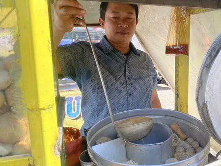 resahnegeri's tweet photo. Jujur... Kalau saya lihat tulisan "Anak Yatim Gratis" di gerobak makanan, pikiran pertama saya pasti promosi.
Biar orang berhenti. Biar dagangannya viral. Saya pikir begitu. Sampai beberapa waktu lalu saya benar-benar mampir ke gerobak yang memasang tulisan itu.

Waktu itu pembelinya lumayan ramai. Anak sekolah. Driver ojol. Pegawai yang baru pulang kerja.
Di depan sebuah minimarket di Jalan Kedinding Lor No 98, Kenjeran, Surabaya. Di gerobak pentolnya tertempel tulisan 'Khusus Anak Yatim Gratis Pentol'.
Saya baca dua kali. Masih nggak percaya.
Pas pembeli mulai sepi, saya iseng nanya.
"Pak."
"Emang sering ada yang gratisan?"
Beliau senyum.
"Iya."
"Nggak takut dimanfaatin orang?"

Beliau cuma ketawa kecil. "Kalau ada yang bohong..."
"Ya itu urusan dia."
"Lagipula... Saya nggak pernah merasa rugi mas. Alhamdulillah justru saya selalu merasa kecukupan. Masih bisa memenuhi kebutuhan keluarga, untuk membayar tanggungan, dan lainnya."
Jawabannya pendek. Tapi entah kenapa saya jadi malu sendiri.

Nggak lama kemudian... Datang dua anak. Masih pakai seragam mengaji. Yang satu langsung berdiri di depan gerobak. Yang satu lagi malah narik lengan temannya.
"Udah... malu."
Suara mereka pelan. Tapi saya dengar.
Bapak itu pura-pura nggak dengar. Beliau malah nanya,
"Mau pedas apa nggak?"
Dua-duanya saling lihat. Nggak ada yang jawab. Akhirnya yang paling kecil ngomong pelan.
"Pak..."
"Saya boleh yang gratis?"

Saya refleks nengok. Anak sekecil itu ngomongnya pelan sekali. Kayak takut ditolak. Bapak itu langsung ambil mangkuk.
"Nggak cuma boleh."
"Hari ini dapat bakso lebih." Beliau nambahin dua butir lagi. Tanpa ditimbang.
Anak itu langsung buru-buru bilang,
"Nggak usah banyak, Pak."
Saya kira karena malu. Ternyata bukan. Dia bilang,
"Nanti adik saya nggak kebagian."
Kalimat itu... Entah kenapa langsung bikin suasana jadi sepi.
Bapak itu berhenti ngaduk kuah.

Beliau lihat anak itu cukup lama. Terus masuk ke gerobaknya lagi. Saya pikir mau ambil sambal. Ternyata beliau ngambil mangkuk satu lagi.
"Ini buat adiknya."
"Nggak usah dibagi."
Anak itu melongo. "Gratis juga, Pak?"
"Iya."
"Tapi..."
"Saya cuma yatim satu orang."
Bapak itu ketawa pelan. "Adikmu kan bukan pembeli."
"Dia tamu saya."
Dua anak itu pulang sambil bawa dua mangkuk.
Saya masih berdiri di situ. Nggak tahu kenapa tenggorokan rasanya berat.

Sebelum saya pergi, saya akhirnya nanya,
"Pak..."
"Kenapa sih Bapak ngelakuin semua ini?"
Beliau nggak langsung jawab. Beliau cuma ngelap mangkuk yang baru dicuci. Terus bilang pelan,
"Dulu saat saya kecil, ibu saya meninggal. Saya merasakan bagaimana tinggal dengan keluarga tidak lengkap. Apalagi kalau ayah yang meninggal, bagaimana susahnya ibu menghidupi anak-anaknya,"

Beliau lanjut ngelap mangkuknya. Seolah kalimat itu biasa saja. Padahal... Sejak pulang hari itu...
Yang terus terngiang di kepala saya bukan tulisan di gerobaknya. Melainkan kebaikan yang begitu tulus. Yang tidak pernah merasa hidupnya dirugikan oleh siapapun.

cc : tubagus_sastra
