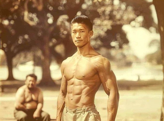 TheBestqueenx's tweet photo. This photo was taken in 1946. 
Meet Ken Shimizu, 35 years old, father of two, who doesn’t exercise, sleeps 10 hours a day, eats whatever he wants, and drinks beer instead of water. 

He has no secret at all. Shimizu is the relaxed guy sitting in the bottom left corner of the photo. 
As for the one hogging the camera in the middle, it is not known who he is.