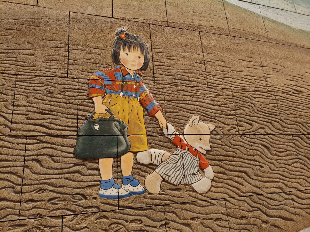 warabekan's tweet photo. こんとあきの舞台、鳥取県にあるわらべ館では、
鳥取県立図書館に寄贈された原画を元にした、砂丘を歩くこんとあきが描かれたレリーフがあります。
県外のファンの方も見に来てくださり、多くの子どもたちが壁画を見て、「こんとあきだー！」と大喜びします。
謹んでお悔やみ申し上げます。 https://t.co/ySlDifGpgD