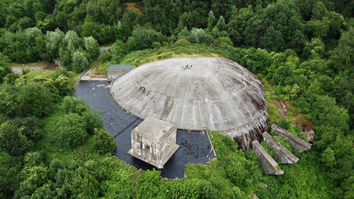 CeJour_Histoire's tweet photo. Au sommet d'une carrière du Pas-de-Calais, une colline cache un dôme de béton de 55 000 tonnes. Vu du ciel, on dirait une soucoupe échouée dans la campagne.

Ce n'est pas un décor de science-fiction. C'est l'une des armes les plus folles de la Seconde Guerre mondiale.

Nous sommes près de Saint-Omer, en 1943. L'Allemagne nazie creuse la craie et coule un dôme de 71 mètres de diamètre, épais de 5 mètres. Dessous, des kilomètres de galeries.

Le projet a un but glaçant : lancer des fusées V2 sur Londres. Quarante à cinquante par jour, à la chaîne.

Pour bâtir ce monstre, des milliers de travailleurs forcés, prisonniers et déportés, s'épuisent sous les bombes.

Le dôme, lui, résiste à tout. Les bombardements alliés labourent la colline autour, sans jamais le percer. Ce qui sauve Londres, ce n'est pas une bombe. C'est le Débarquement, qui arrive avant que la base ne tire un seul missile.

La guerre finie, l'ironie est totale. L'ingénieur des V2, Wernher von Braun, partira aux États-Unis. Ses fusées conduiront un homme sur la Lune.

Aujourd'hui, sous le béton, un musée raconte tout ça.

Vous connaissiez ce lieu ?