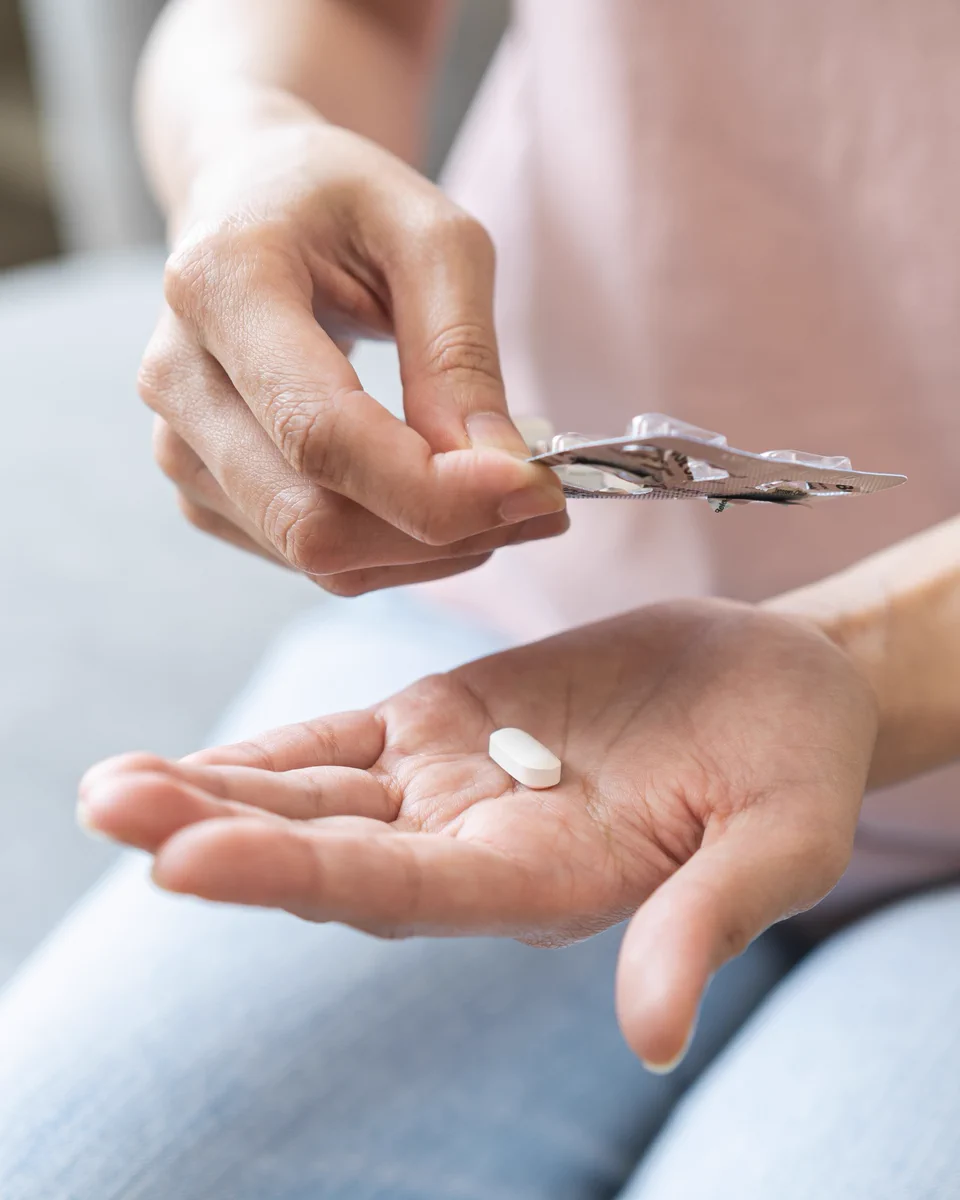 Person pushes a tablet out of a blister pack onto their palm