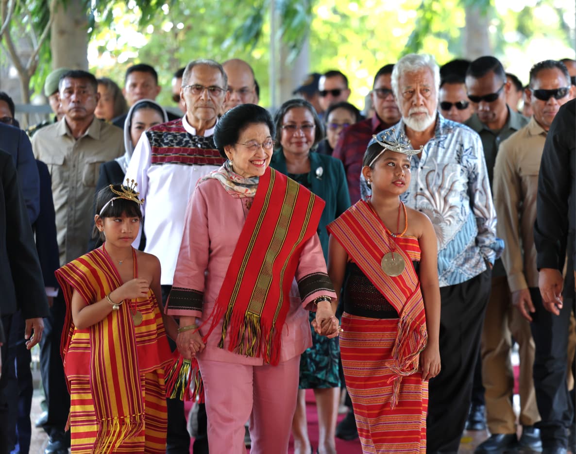GunRomli's tweet photo. Ibu Megawati Soekarnoputri Tiba di Timor-Leste, Disambut Hangat Tokoh Penting dan Lambaian Bendera Anak Sekolah

Kunjungan ke Timor-Leste: Ibu Megawati Disambut Karpet Merah, Tarian Tradisional, hingga Antusiasme Pelajar

Mendarat di Dili, Ibu Megawati Soekarnoputri Terima Penyambutan Agung dari Pemerintah Timor-Leste

DILI – Presiden Kelima Republik Indonesia yang juga Ketua Umum PDI Perjuangan, Prof. DR. Megawati Soekarnoputri, melakukan kunjungan resmi ke Timor-Leste.

Menggunakan pesawat yang mendarat di Bandara Internasional Presidente Nicolau Lobato, Dili, rombongan Ibu Megawati tiba pada Rabu (8/7/2026), pukul 16.10 waktu setempat.

Begitu pesawat berhenti, Direktur Jenderal Urusan Protokol dari Kementerian Luar Negeri dan Kerja Sama Timor-Leste, Josefina Tilman, langsung naik ke pesawat untuk menyambut dan mendampingi Megawati turun menuju apron bandara.

Di kaki tangga pesawat, jajaran pejabat tinggi negara telah bersiap menyambut kedatangan beliau. Di antaranya adalah Wakil Perdana Menteri sekaligus Menteri Koordinator Bidang Perekonomian, Pariwisata, dan Lingkungan Hidup Timor-Leste, Francisco Kalbuadi Lay.

Turut hadir pula Kuasa Usaha Ad Interim (KUAI) Kedutaan Besar Republik Indonesia (KBRI) untuk Timor-Leste, Ibu Mardiana Warnares.

Prosesi penyambutan dilanjutkan dengan berjalan di atas karpet merah, di mana Ibu Megawati diapit oleh pasukan tradisional Moradores yang disiapkan oleh Kantor Penghubung Militer (Casa Militar) Kepresidenan Timor-Leste.

Ibu Megawati tiba didampingi keluarganya seperti Puti Guntur Soekarnoputri dan Romy Soekarno, serta jajaran partai seperti Sekretaris Jenderal PDI Perjuangan Hasto Kristiyanto dan Ketua DPP PDI Perjuangan Bintang Puspayoga.

Ibu Megawati lalu berjalan menuju sejumlah tokoh yang sudah lebih dulu bersiap untuk menerima kunjungannya. Termasuk Presiden Republik Timor-Leste, J. Ramos Horta, Perdana Menteri Rala Xanana Gusmão, Menteri Luar Negeri dan Kerja Sama Bendito dos Santos Freitas, dan Kepala Staf Kepresidenan Henriqueta M. da Silva.

Dari pihak Indonesia, sejumlah petinggi PDI Perjuangan seperti Ketua DPP PDIP yang juga Wakil Ketua Komisi XIII DPR-RI Andreas H. Pareira, Ketua DPP PDI Perjuangan bidang Luar Negeri Ahmad Basarah, Kepala Badan Riset dan Analisis Kebijakan Pusat Partai Andi Widjajanto, juga ikut dalam delegasi penyambutan.

Setelah bersalaman hangat dengan Ramos Horta, Xanana, dan pejabat Timor Leste lainnya, Ibu Megawati lalu disambut dengan tarian adat setempat. Ibu Megawati tampak menyapa para penari dengan senyuman manisnya.

Setelah itu, Ibu Megawati berjalan lagi dan dua orang gadis berpakaian adat setempat mempersembahkan buket bunga dan kain adat berwarna merah. Salah seorang anak perempuan kecil yang menyambutnya lalu mengalungkan kain itu.

Ibu Megawati lalu mengajak kedua anak perempuan itu berjalan bersama. Ia gandeng tangan kedua putri Timor itu di kanan san kirinya, dan berjalan bersama ke arah gedung kedatangan di bandara. Ramos Horta, Xanana, dan seluruh yang hadir menyambut, mengikuti di belakang.

Suasana hangat dan meriah tidak hanya terasa di dalam area bandara. Saat iring-iringan kendaraan Ibu Megawati Soekarnoputri mulai bergerak keluar dari kompleks Bandara Internasional Presidente Nicolau Lobato, ribuan anak sekolah telah bersiap di sepanjang jalan dari bandara menuju tempat penginapan.

Dengan penuh antusias, para pelajar tersebut mengibas-ngibaskan bendera kedua negara sebagai bentuk penghormatan dan sambutan hangat dari generasi muda Timor-Leste untuk menyambut kehadiran pemimpin perempuan pertama Indonesia tersebut.

Untuk diketahui, kunjungan kenegaraan Megawati ini akan berlangsung hingga 10 Juli 2026. Agenda utamanya adalah menerima penghargaan tertinggi Grand Collar of Timor Leste atas jasanya dalam memajukan hubungan bilateral dan rekonsiliasi kedua negara dari Presiden Jose Ramos-Horta...